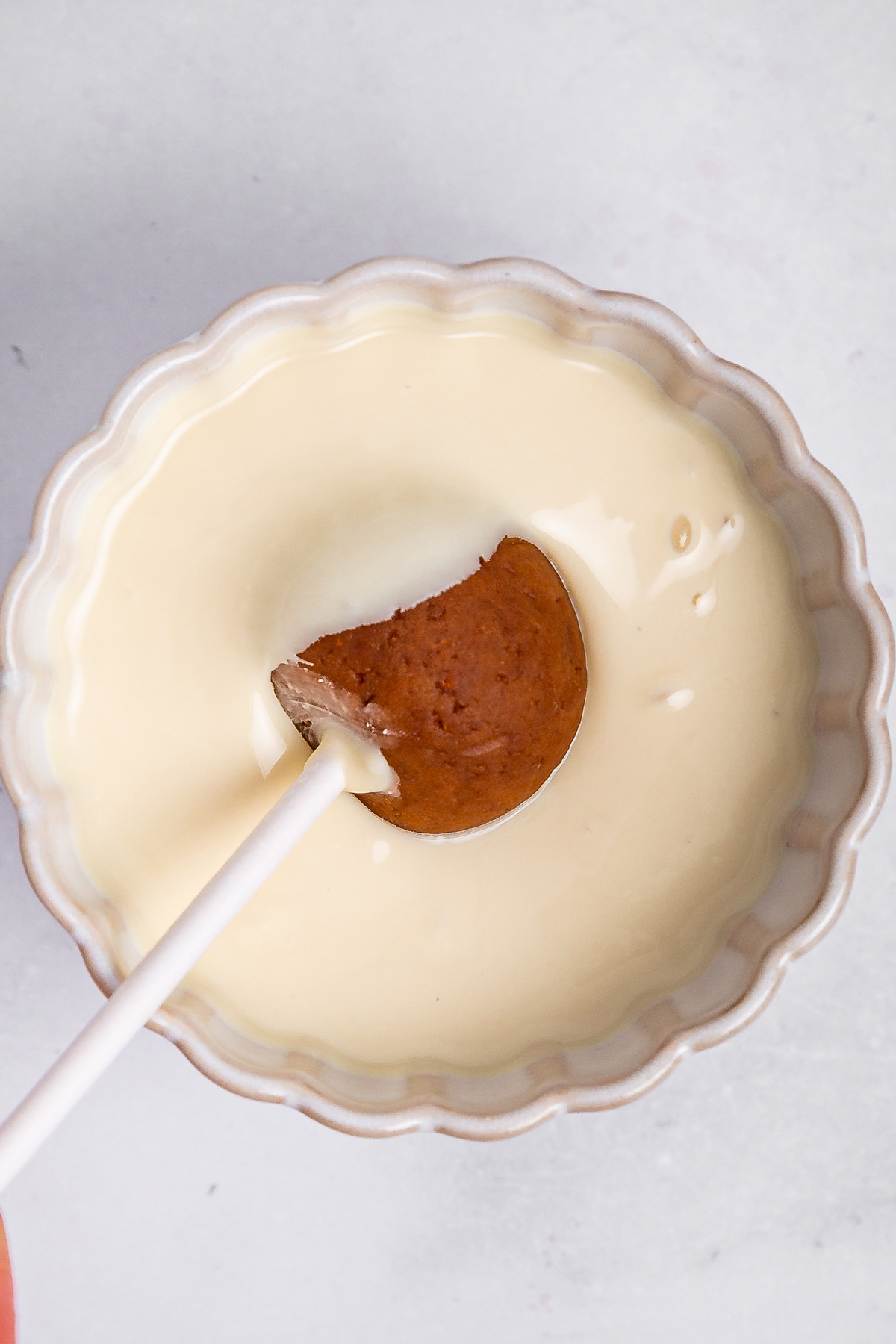 dipping biscoff cake pop into melted white chocolate
