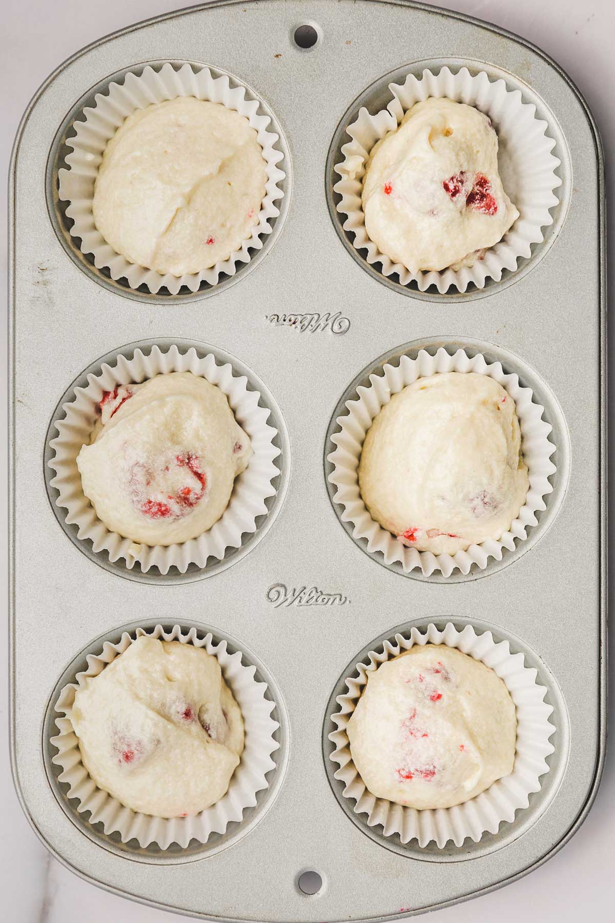 cupcake pan with raspberry cupcake batter