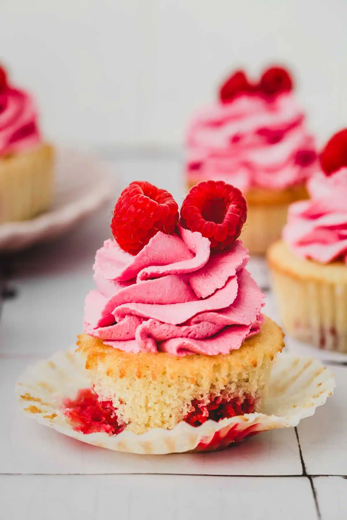 one raspberry cupcake with a raspberry frosting on a table