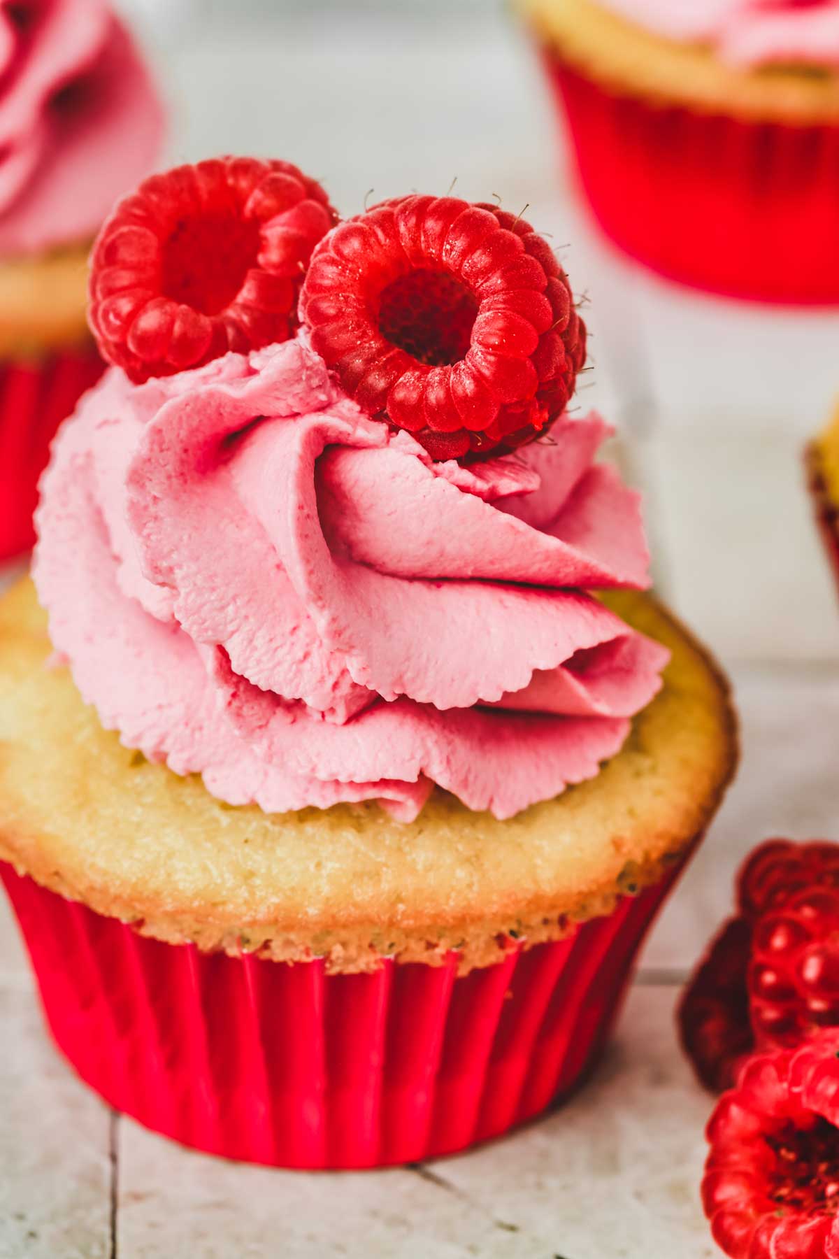 one cupcake with pink raspberry whipped cream frosting