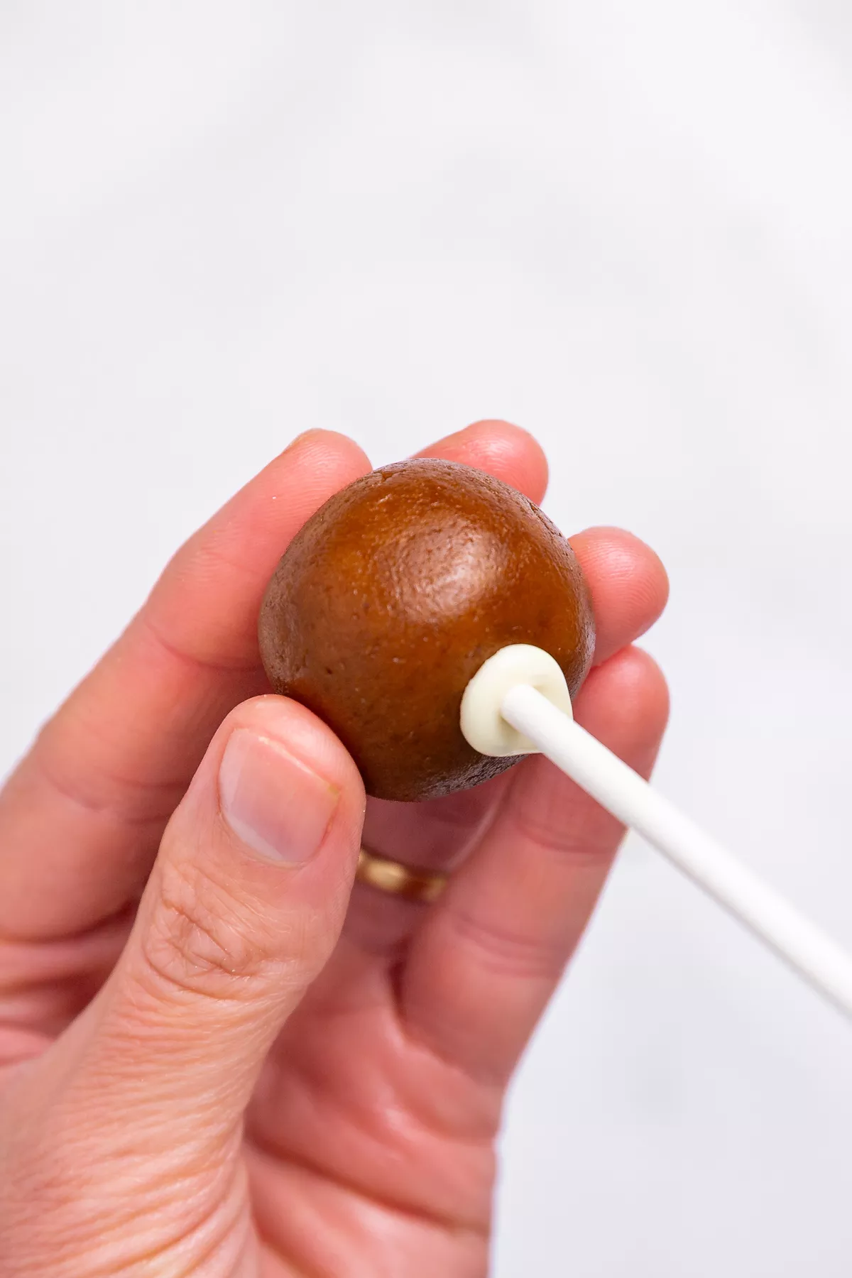 inserting a stick into a biscoff cake pop ball