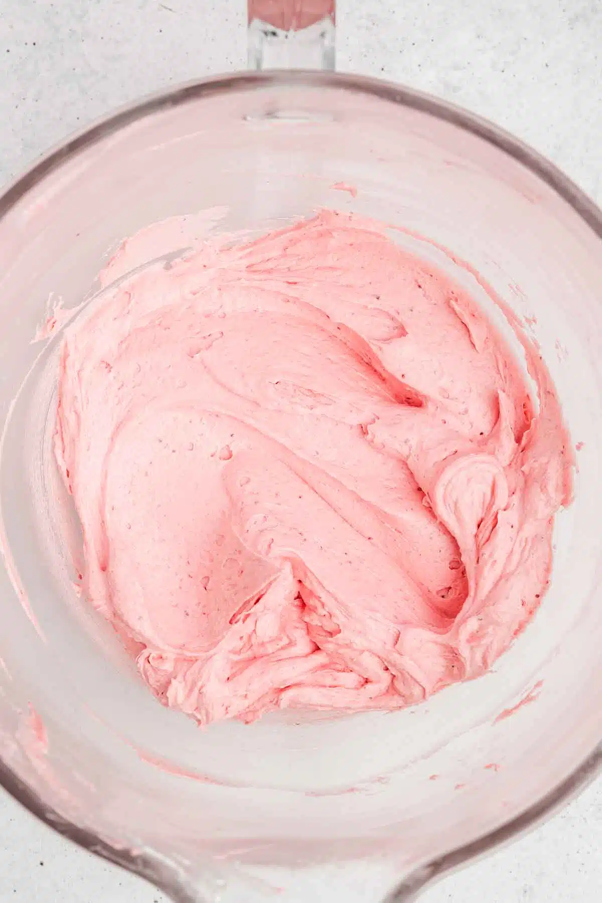 large mixing bowl with pink strawberry butting frosting