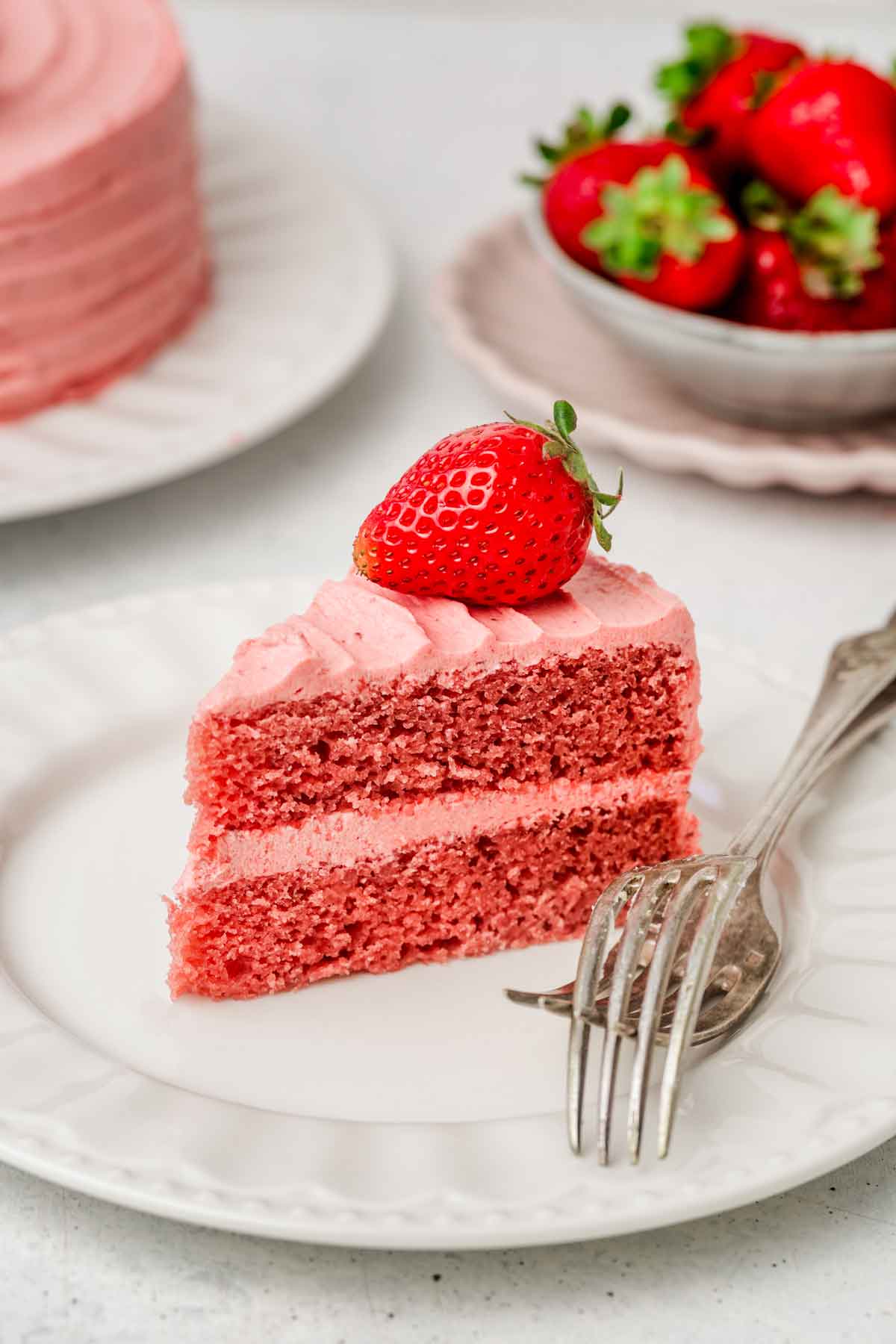 part de gâteau aux fraises dans une assiette avec une fraise dessus