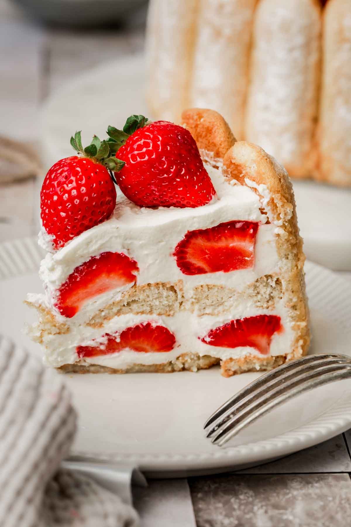 sliced strawberry charlotte cake on a dessert plate