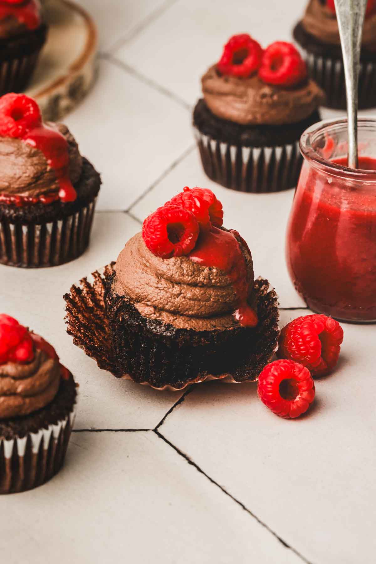 cupcakes au chocolat sur une table avec de la ganache et des framboise