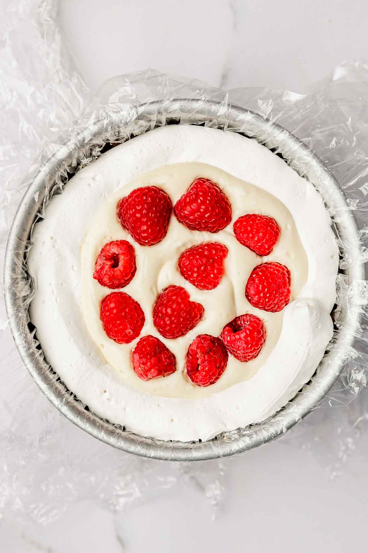 cake pan with layer of cake and fresh raspberries