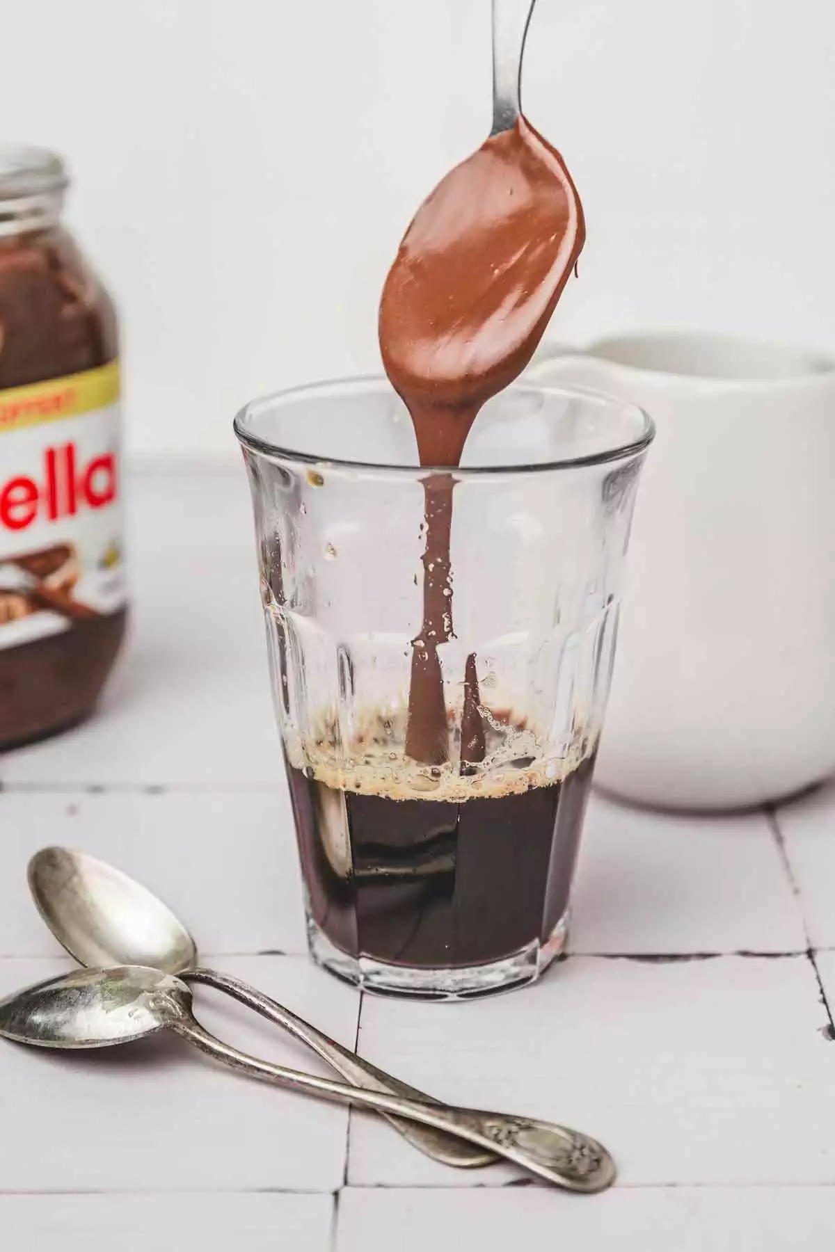 un verre avec un café espresso et une cuillère de nutella