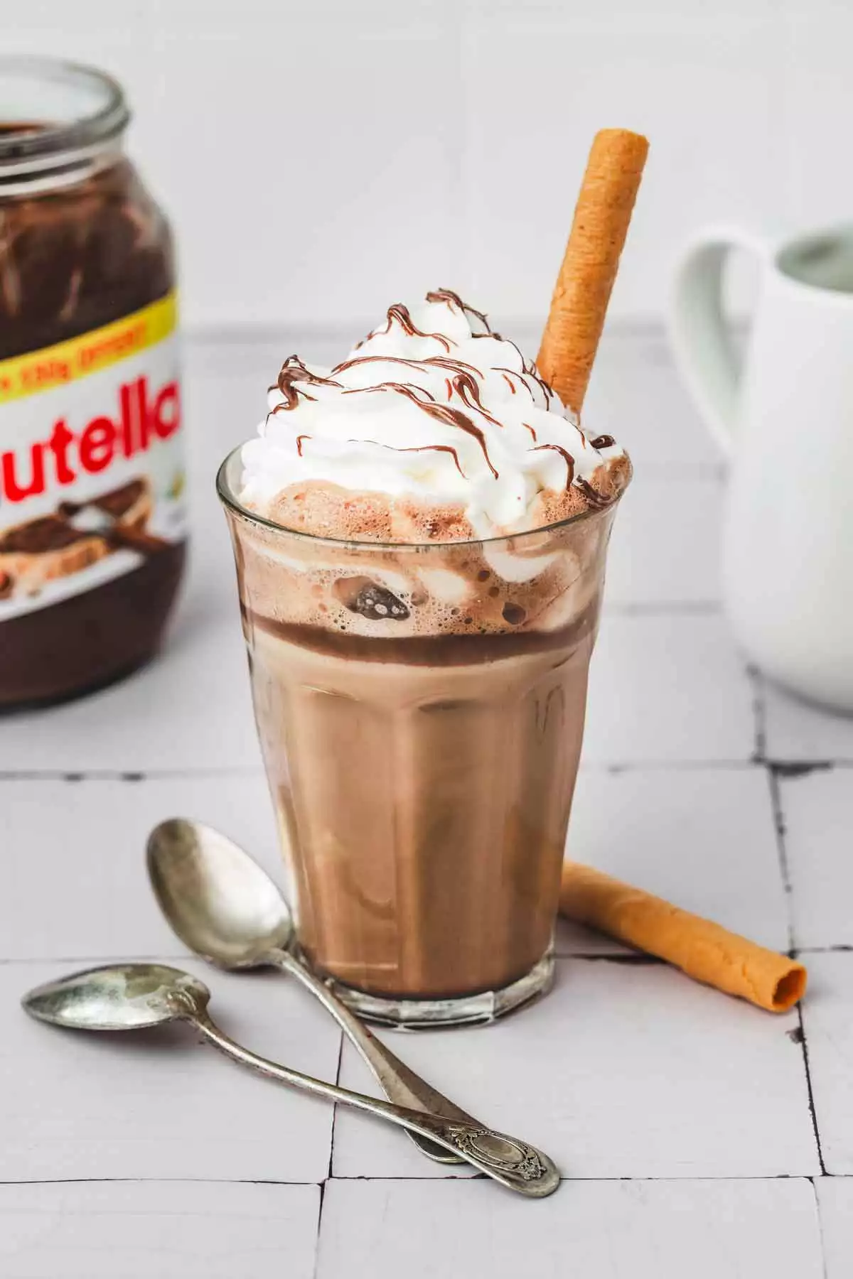 verre avec un latte café au nutella de la chantilly et un biscuit