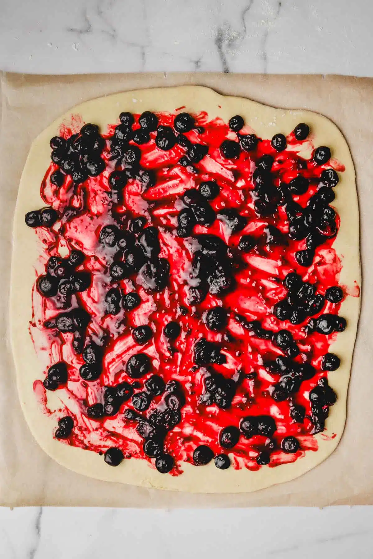 spread out brioche dough filled with a blueberry mixture