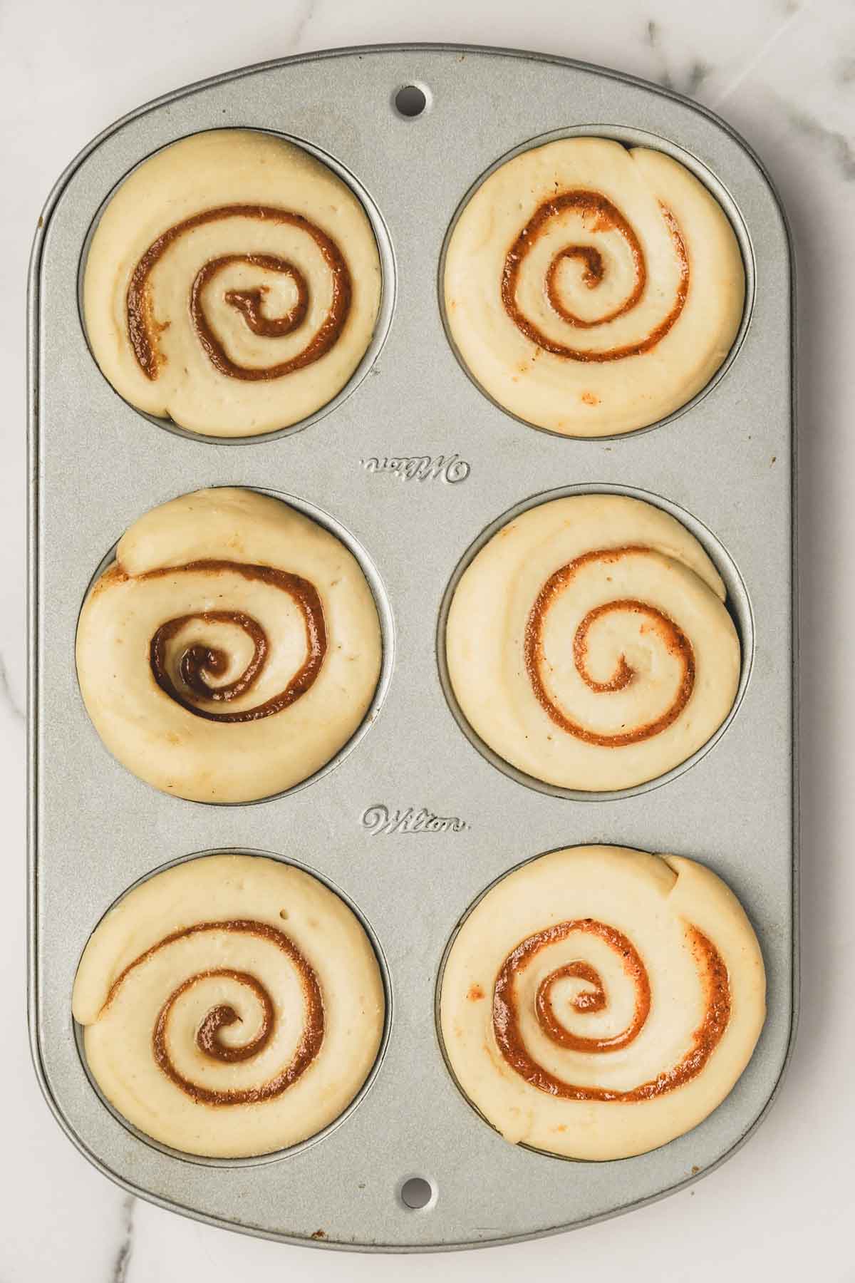 cinnamon roll dough in a muffin pan