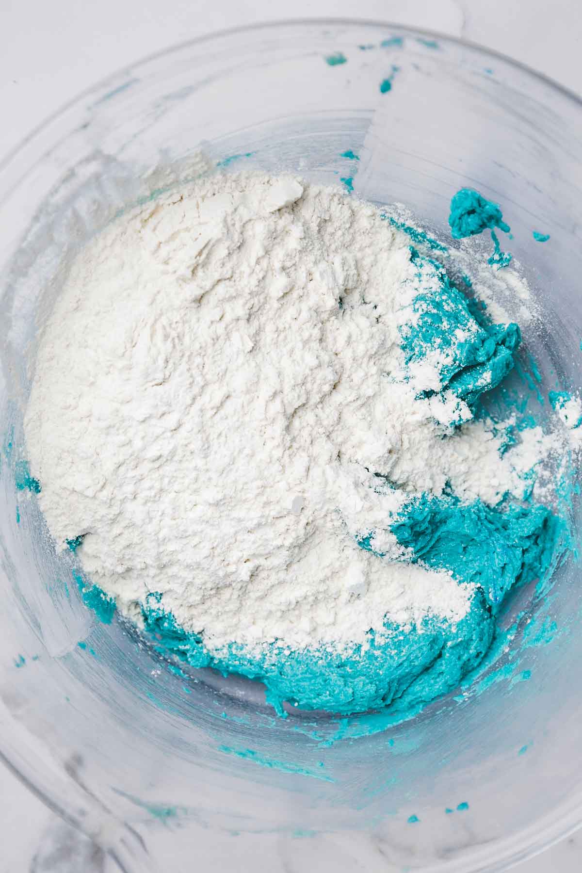 mixing bowl with blue batter and dry ingredient