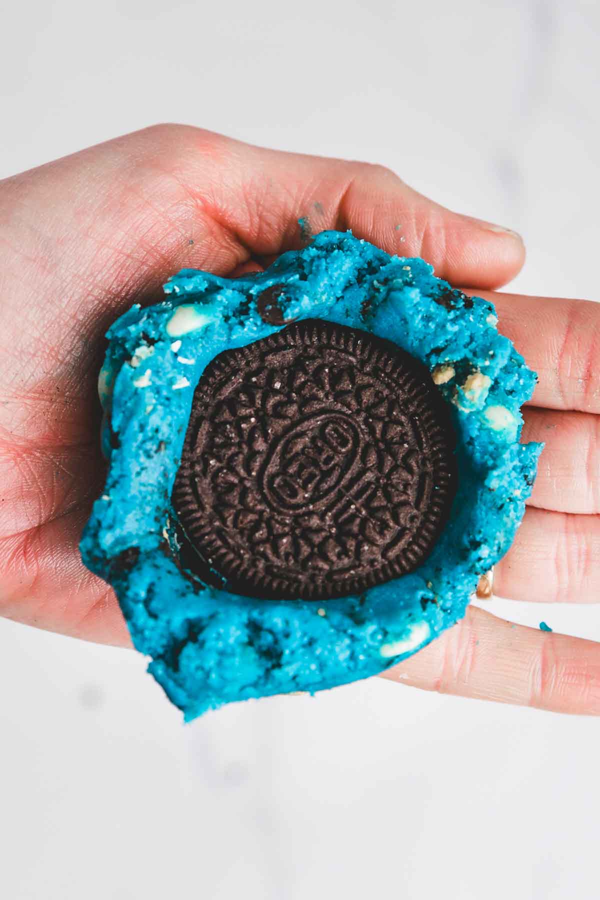 hand with cookie batter and a whole oreo