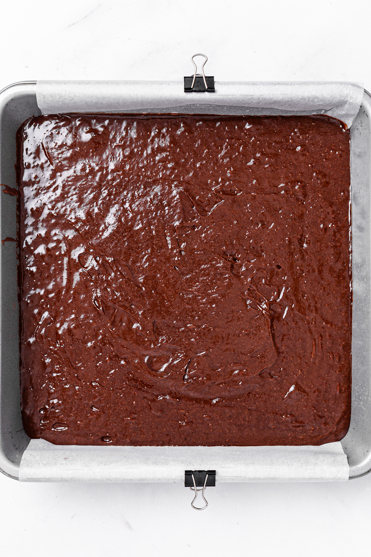 fudgy brownie batter spread in a baking pan before baking