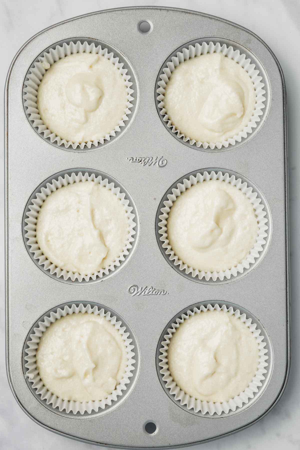 muffin pan with vanilla cupcake batter