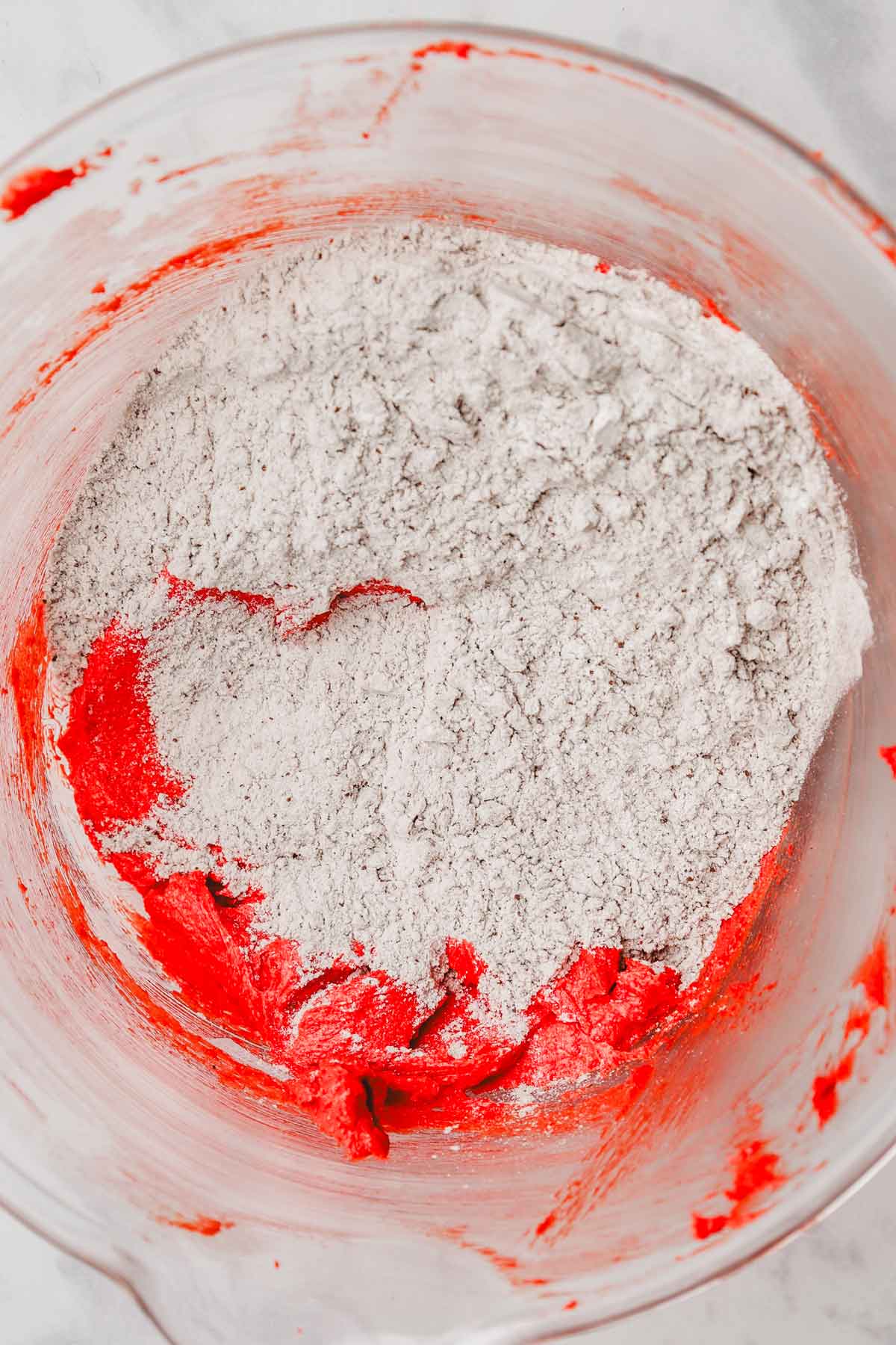 mixing bowl with red cookie dough with flour mixture