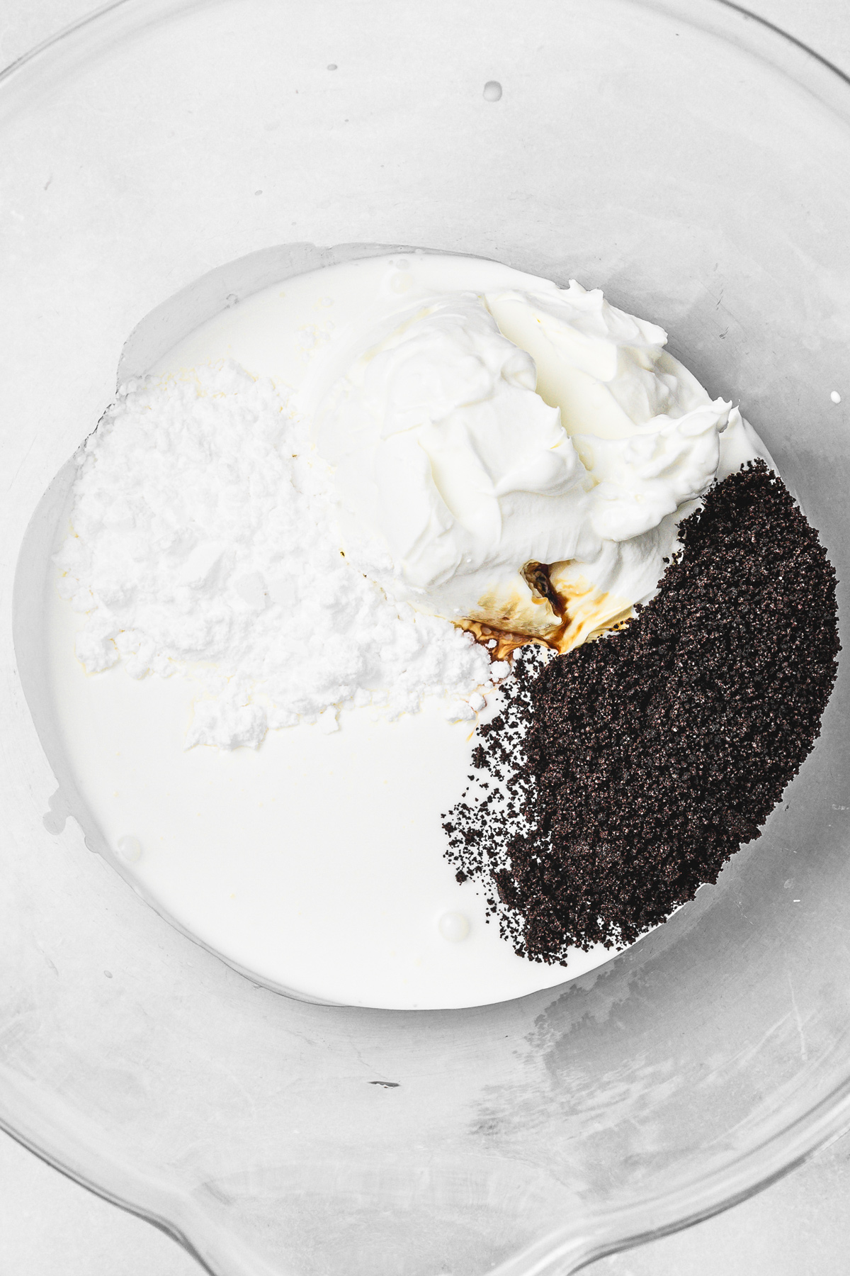 mixing bowl with ingredients to make oreo cream cheese frosting before whipping
