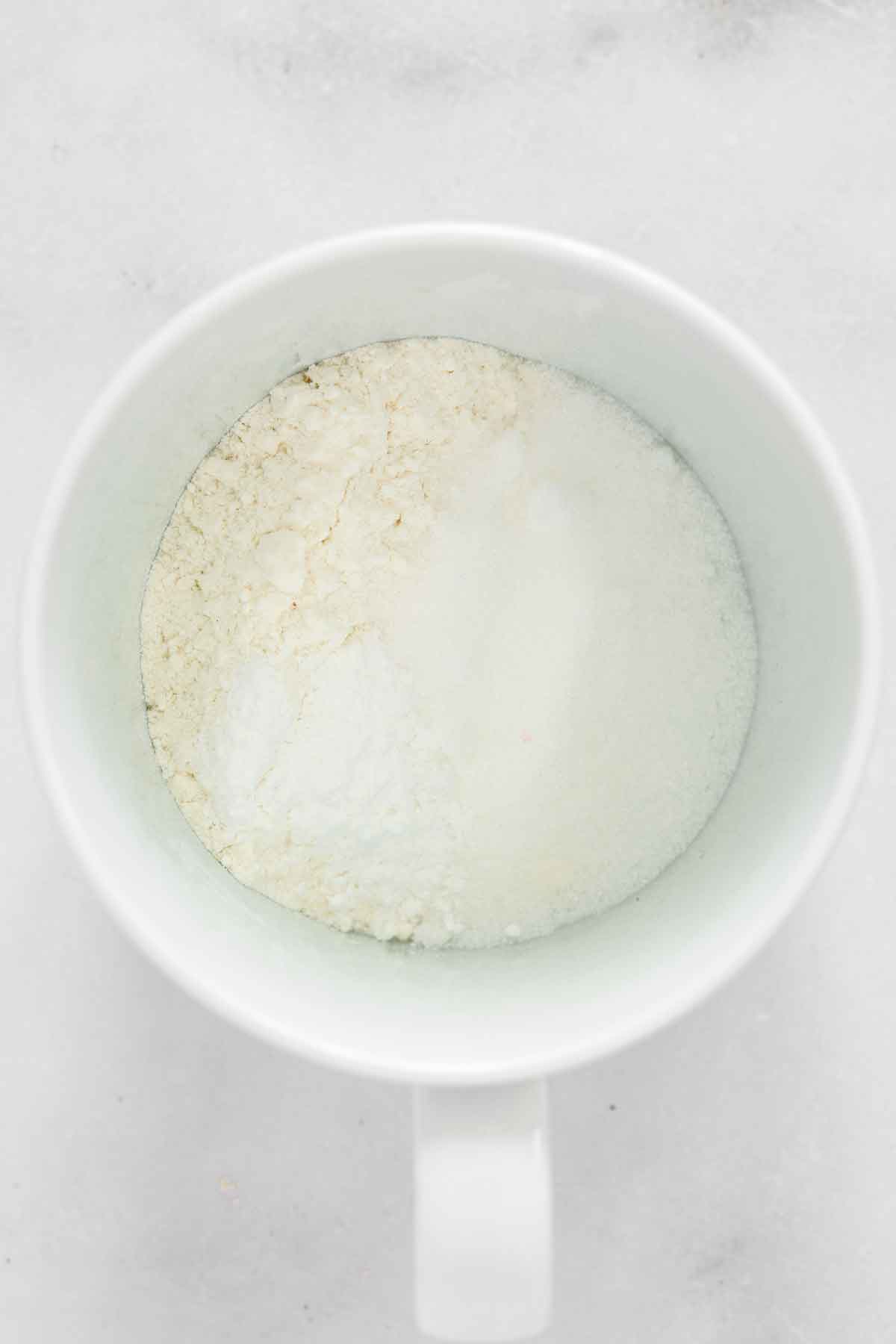 flour, sugar and baking powder mixture in mug

