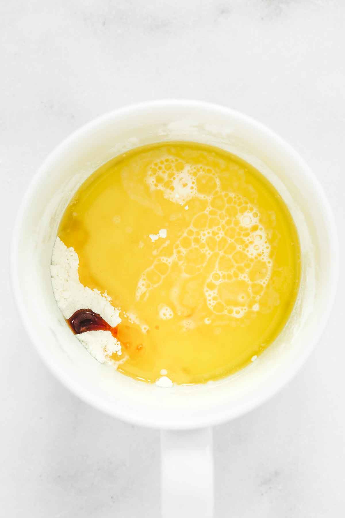 adding melted butter and milk to mug cake batter
