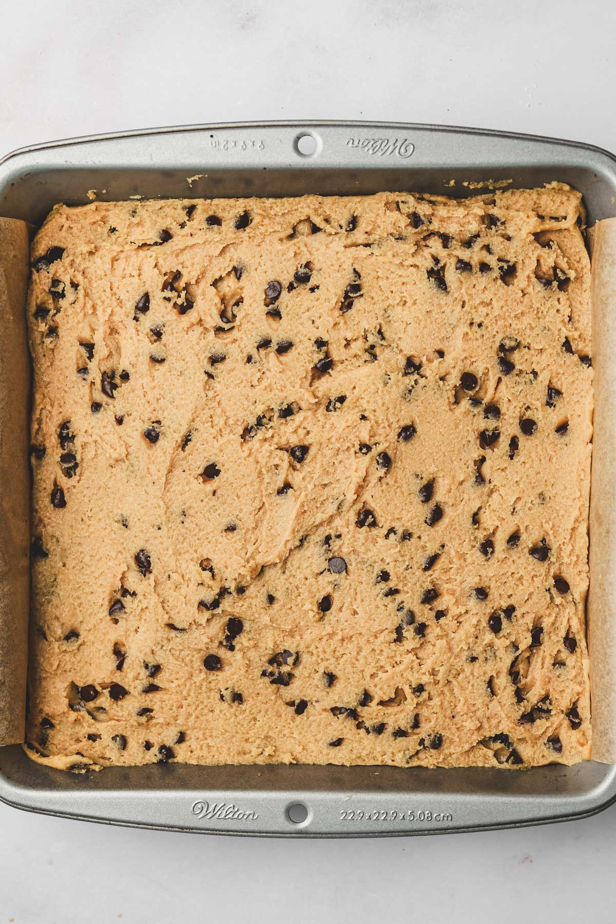 square pan with a layer of chocolate chip cookie batter