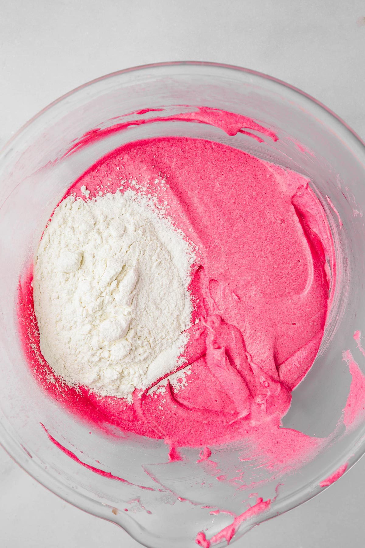 mixing bowl with pink cake batter and flour mixture