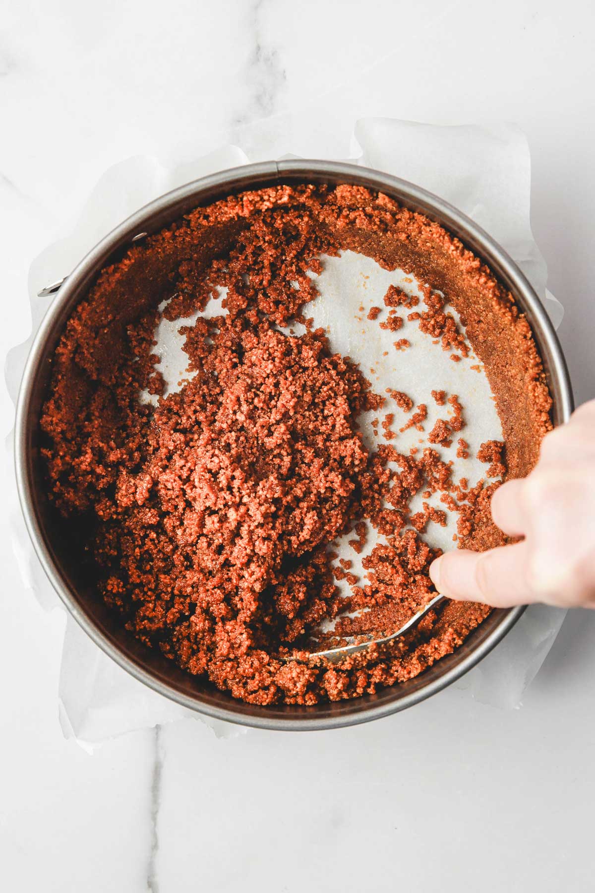 pressing biscoff crust up the sides of a springform pan