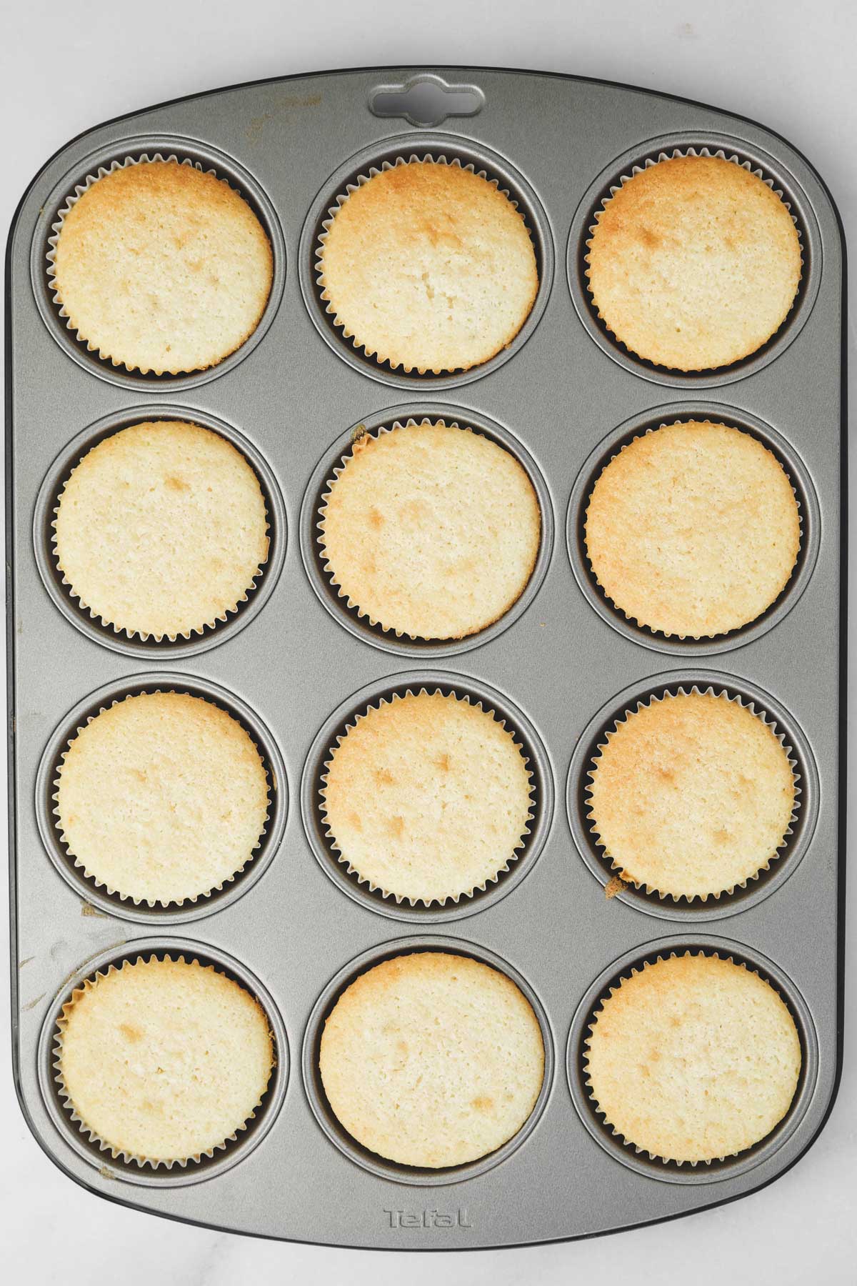 muffin pan with baked cupcakes batter