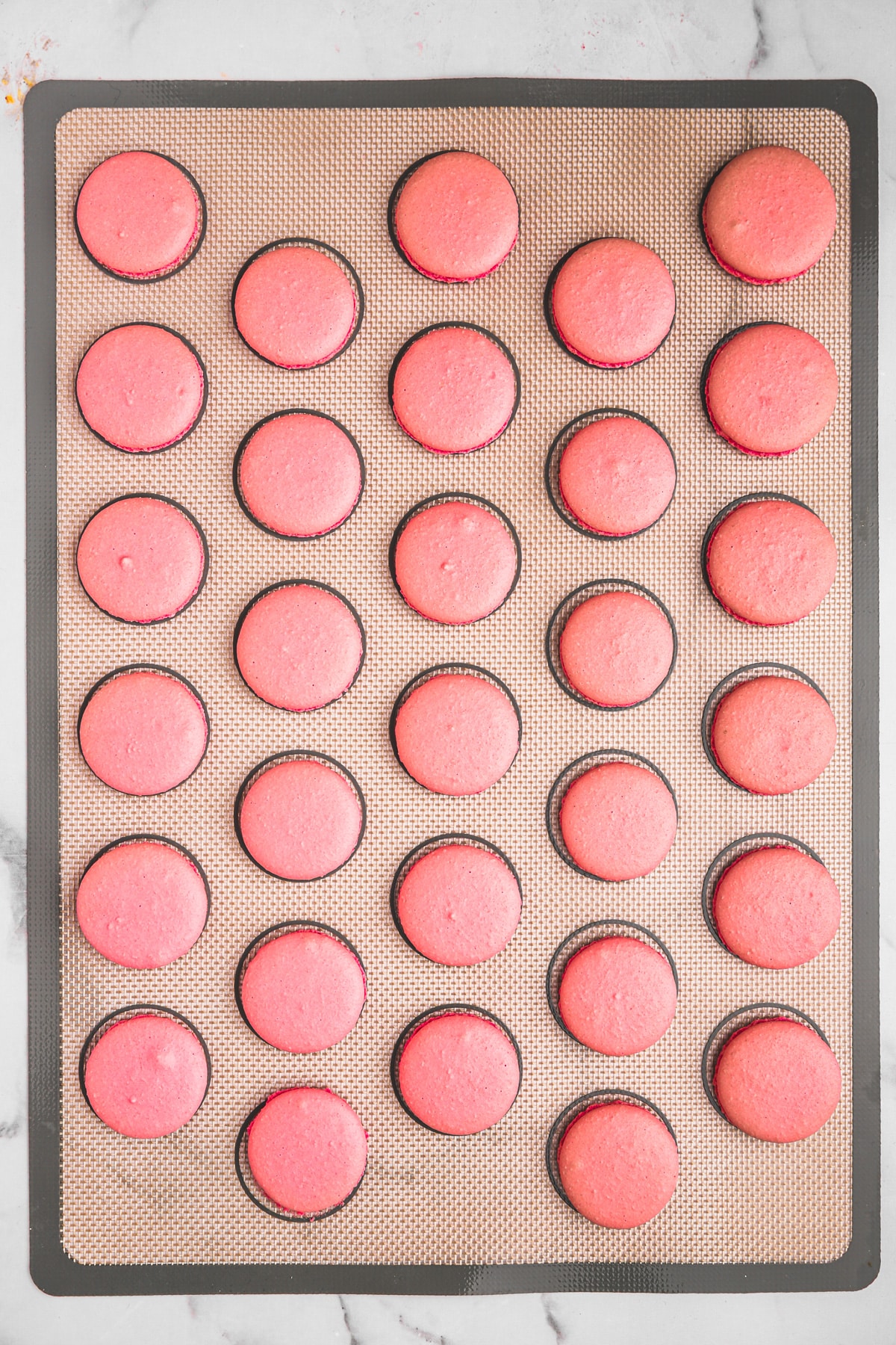 plaque en silicone avec coques de macarons roses cuites