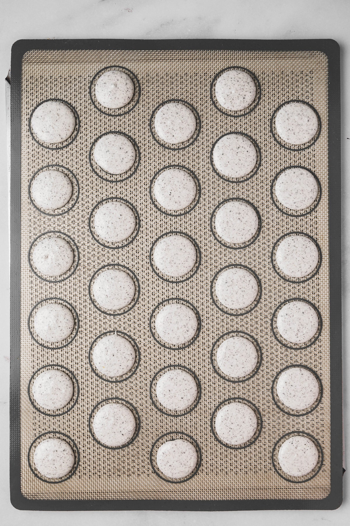 piped Oreo macaron batter on silicone mat