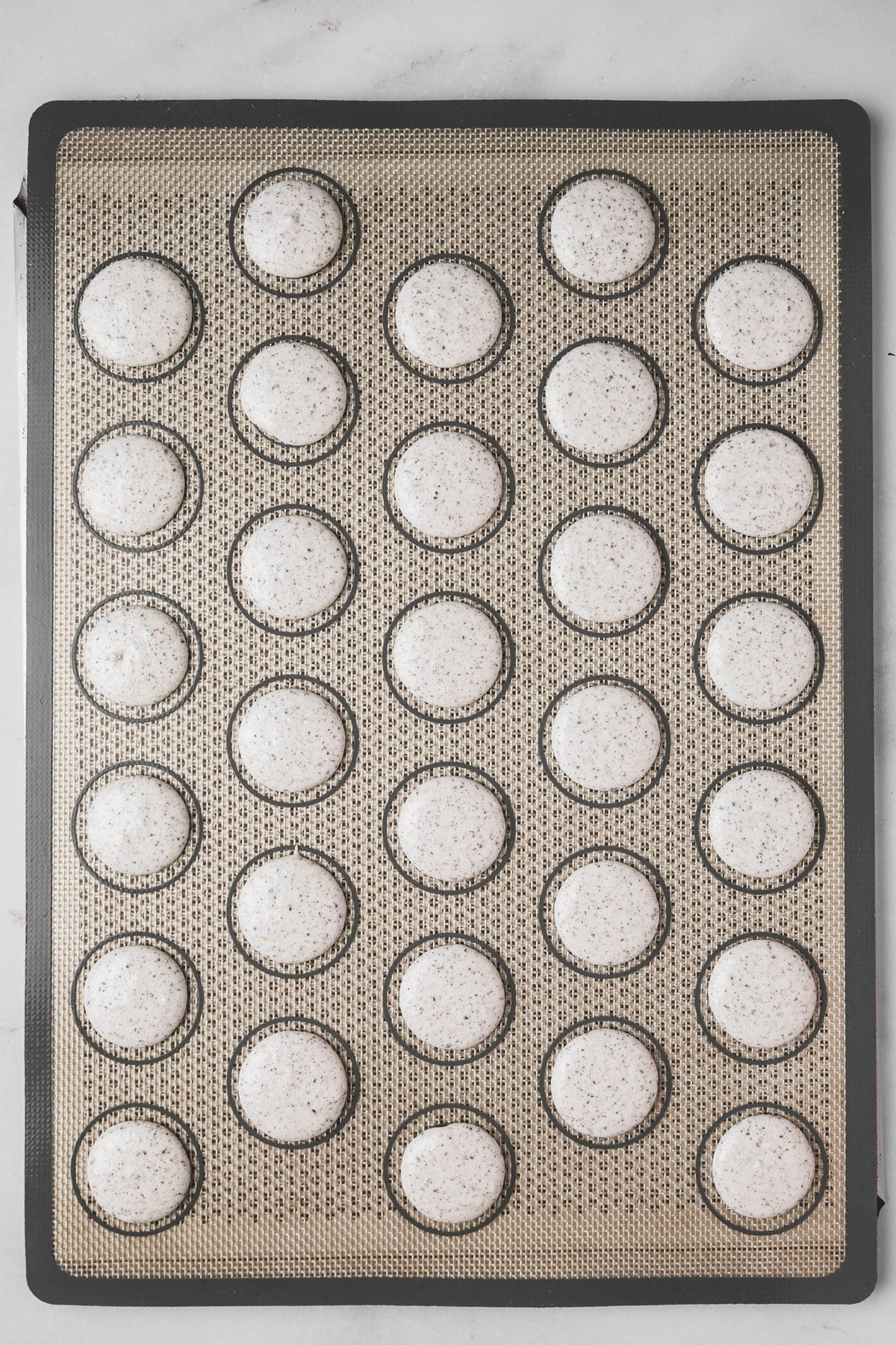 piped Oreo macaron batter on silicone mat