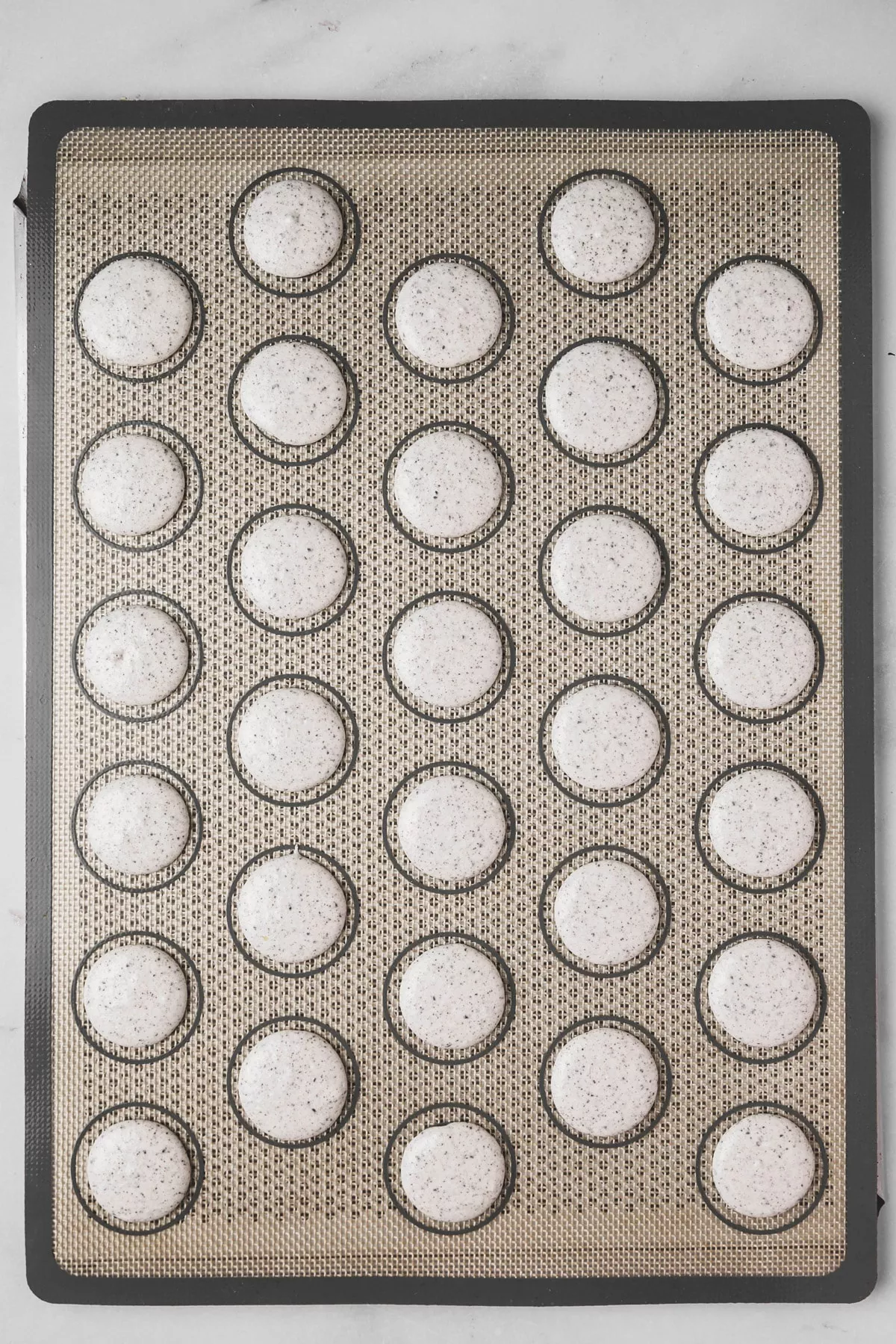 piped Oreo macaron batter on silicone mat