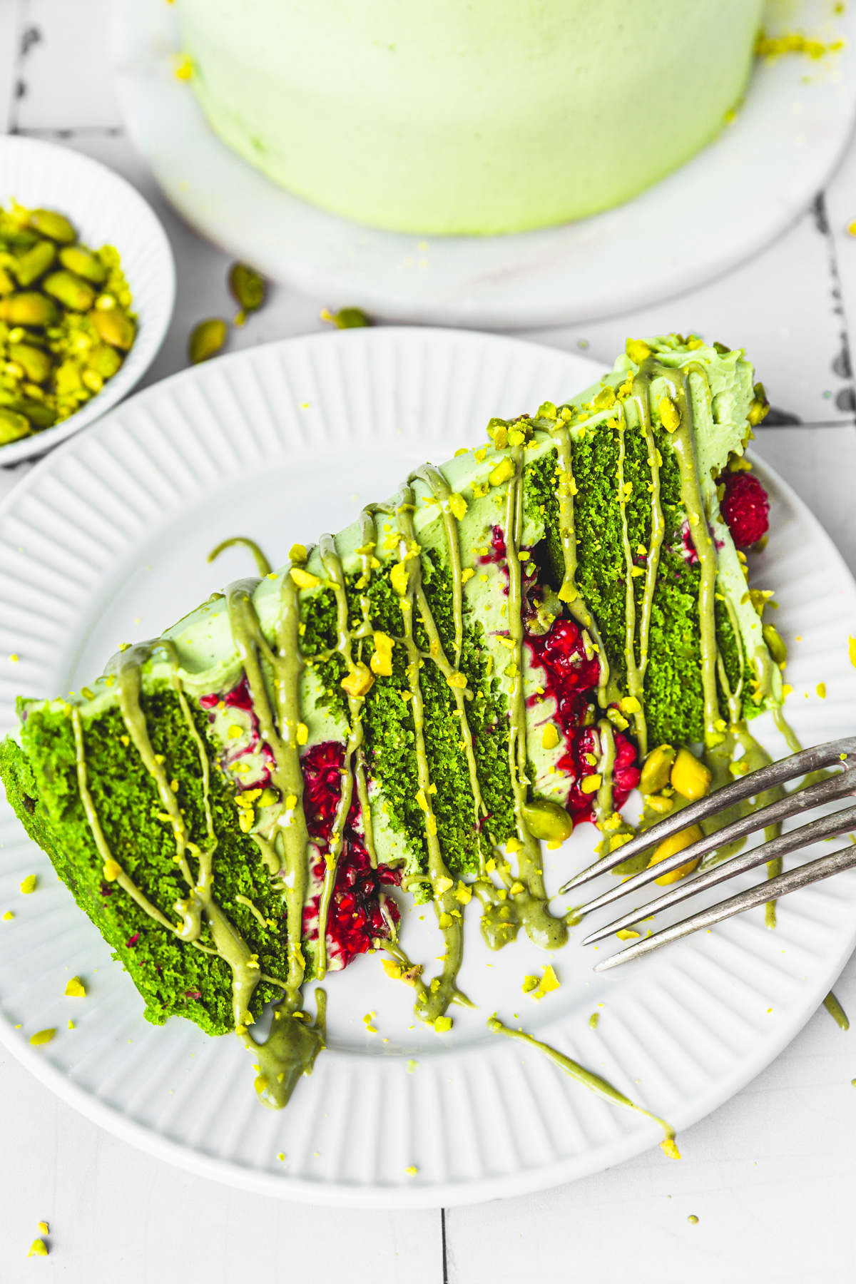 part de layer cake pistache framboise sur une assiette