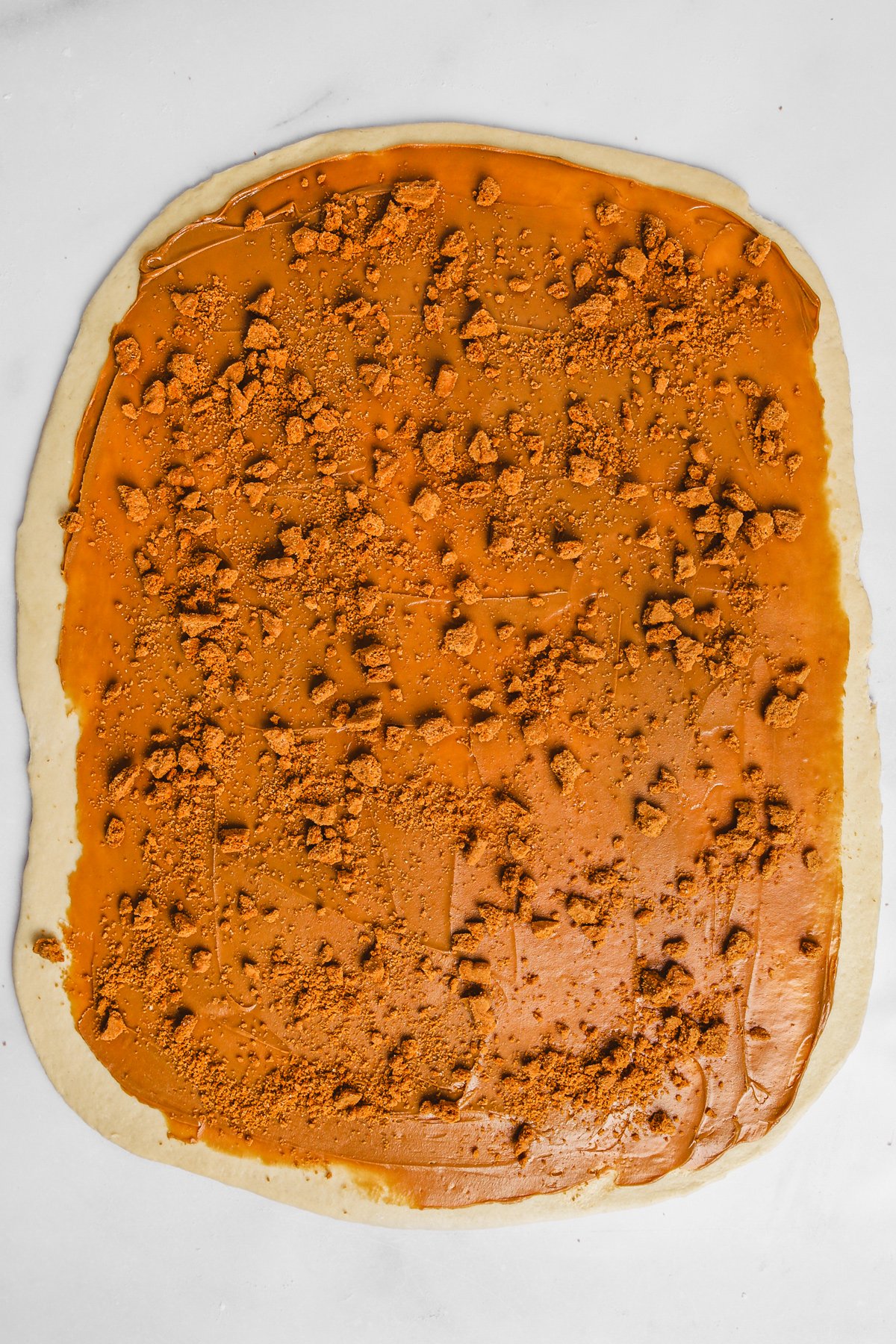 Rolled out brioche dough spread with Biscoff cookie butter and crushed Biscoff cookies