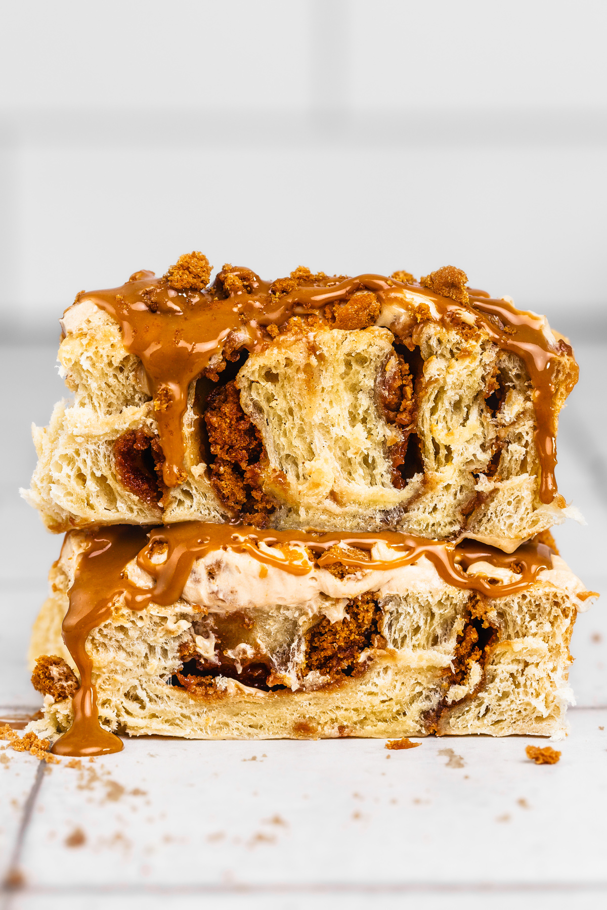 Two pieces of Biscoff cinnamon rolls with melting cookie butter frosting and cream cheese glaze