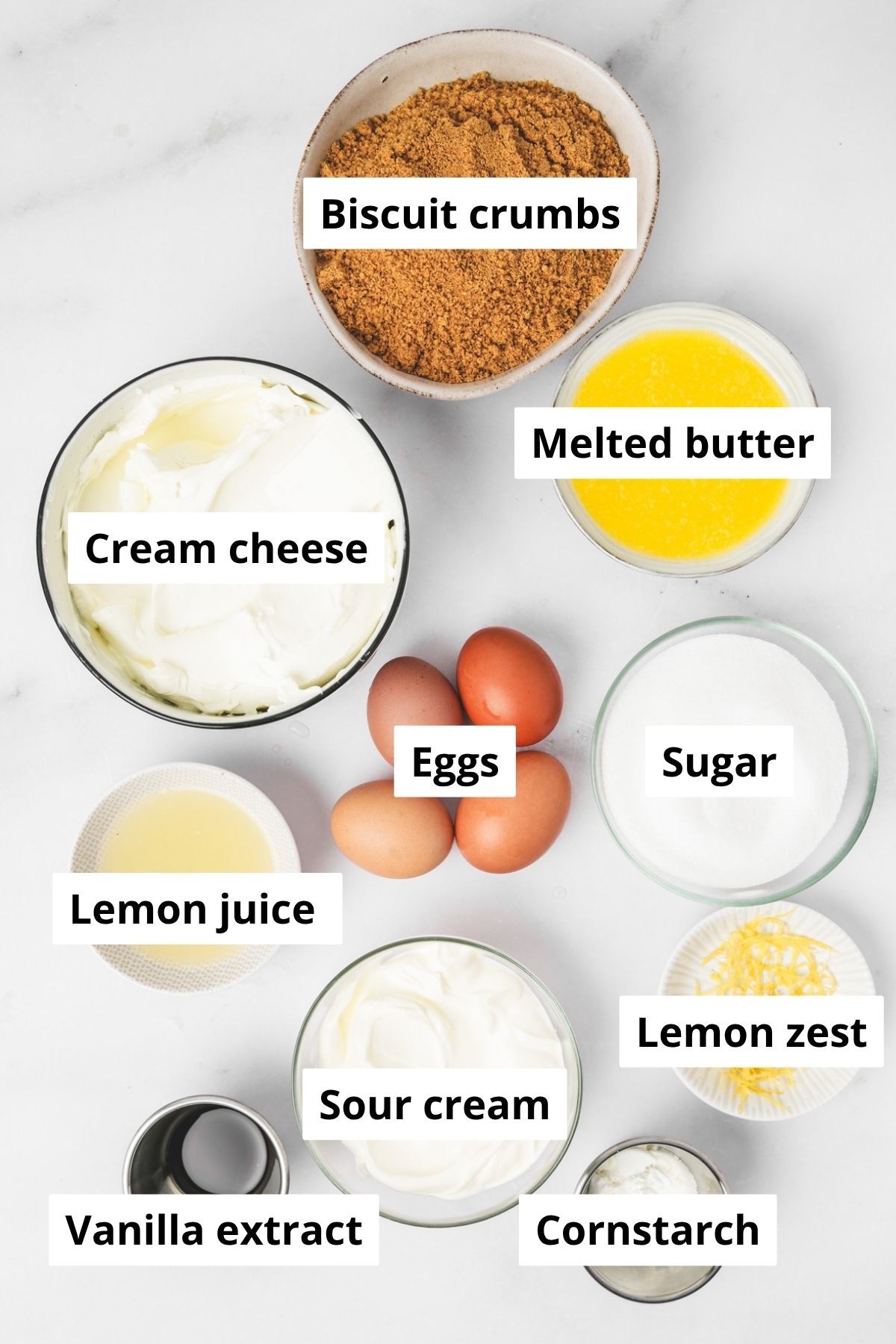 Ingredients for lemon meringue pie cheesecake including cream cheese, eggs, lemons, and graham crackers