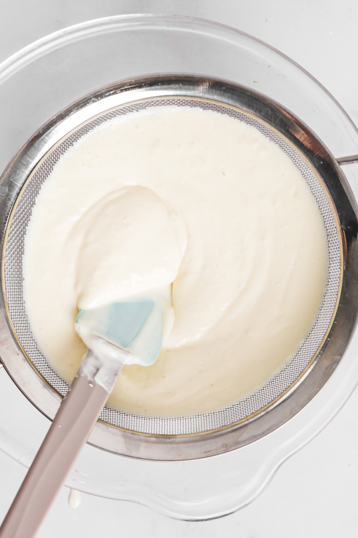 Sifting the lemon cheesecake batter for a smooth texture