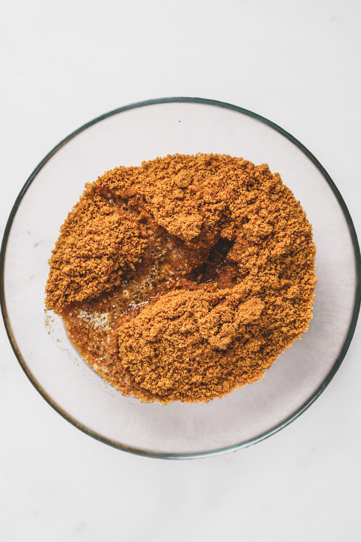 Mixing graham cracker crumbs and melted butter for the cheesecake crust