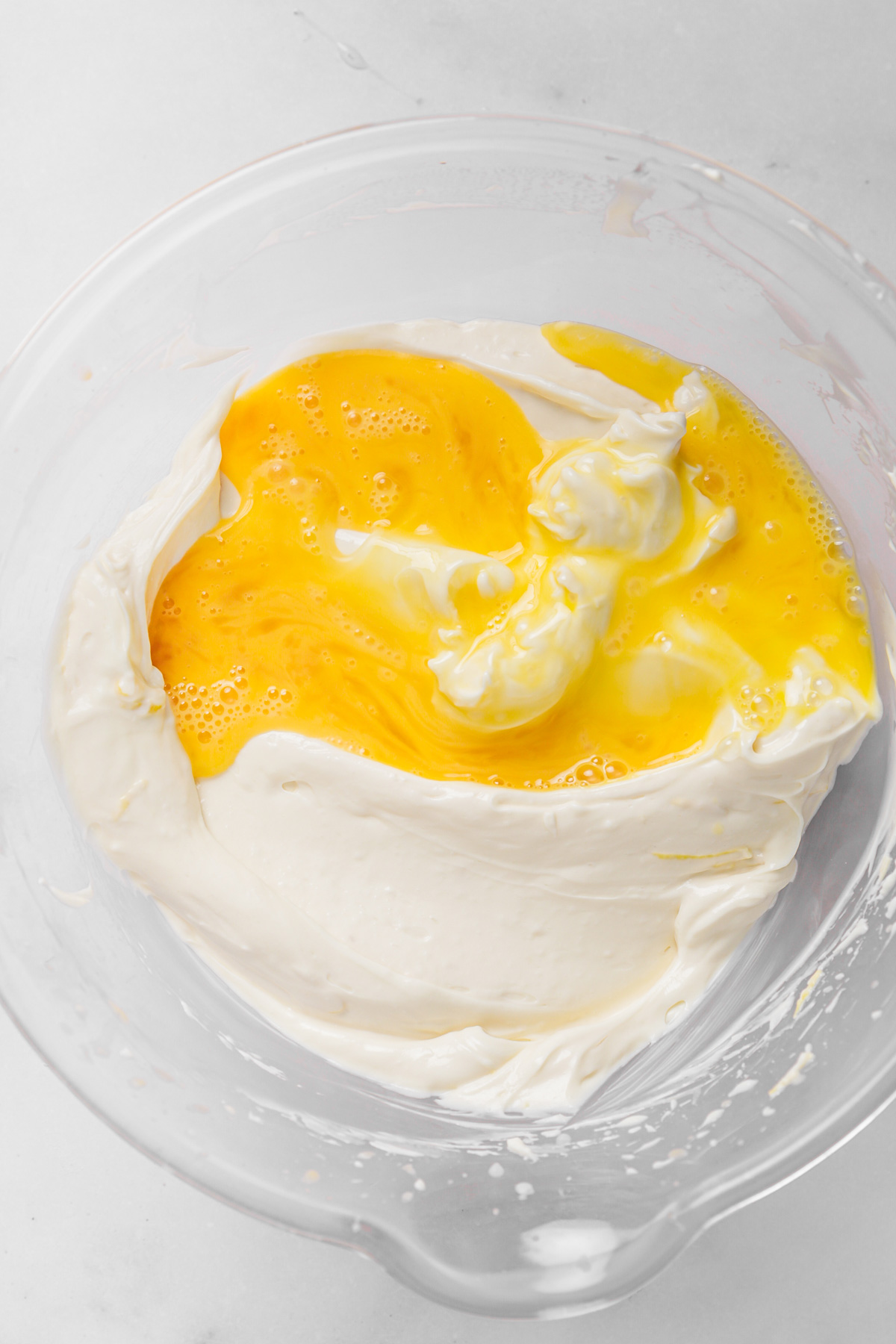 Whisking eggs into lemon cheesecake batter for a creamy filling
