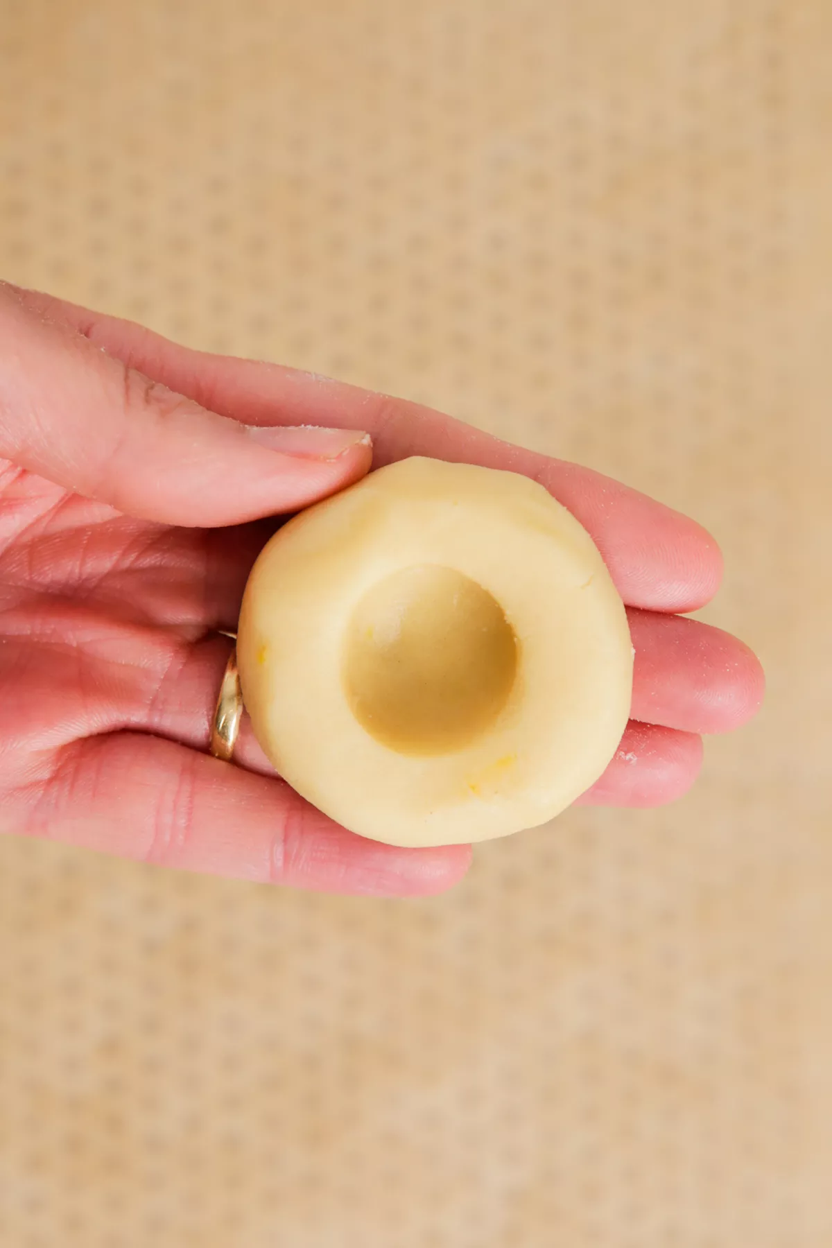 hand pressing dough to shape lemon thumbprint cookies
