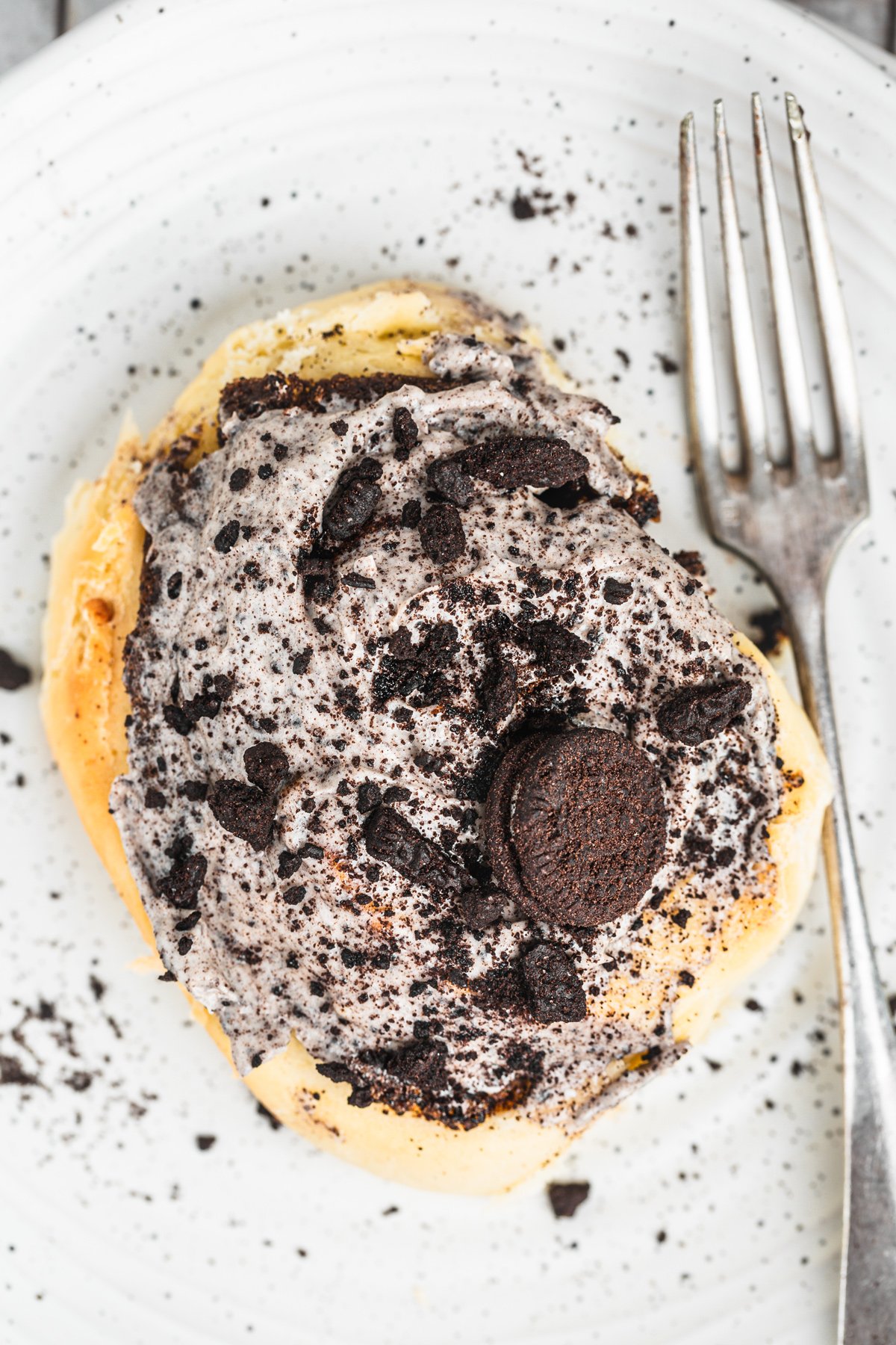Single Oreo cinnamon roll served on a plate with creamy glaze