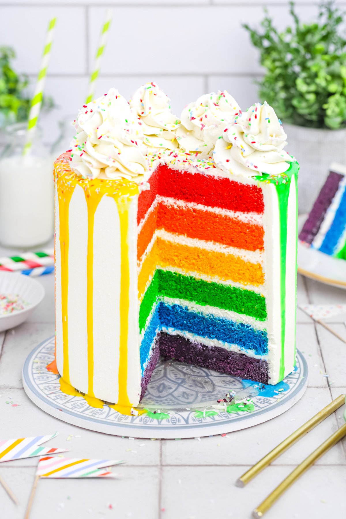 Rainbow cake on a table with one slice removed