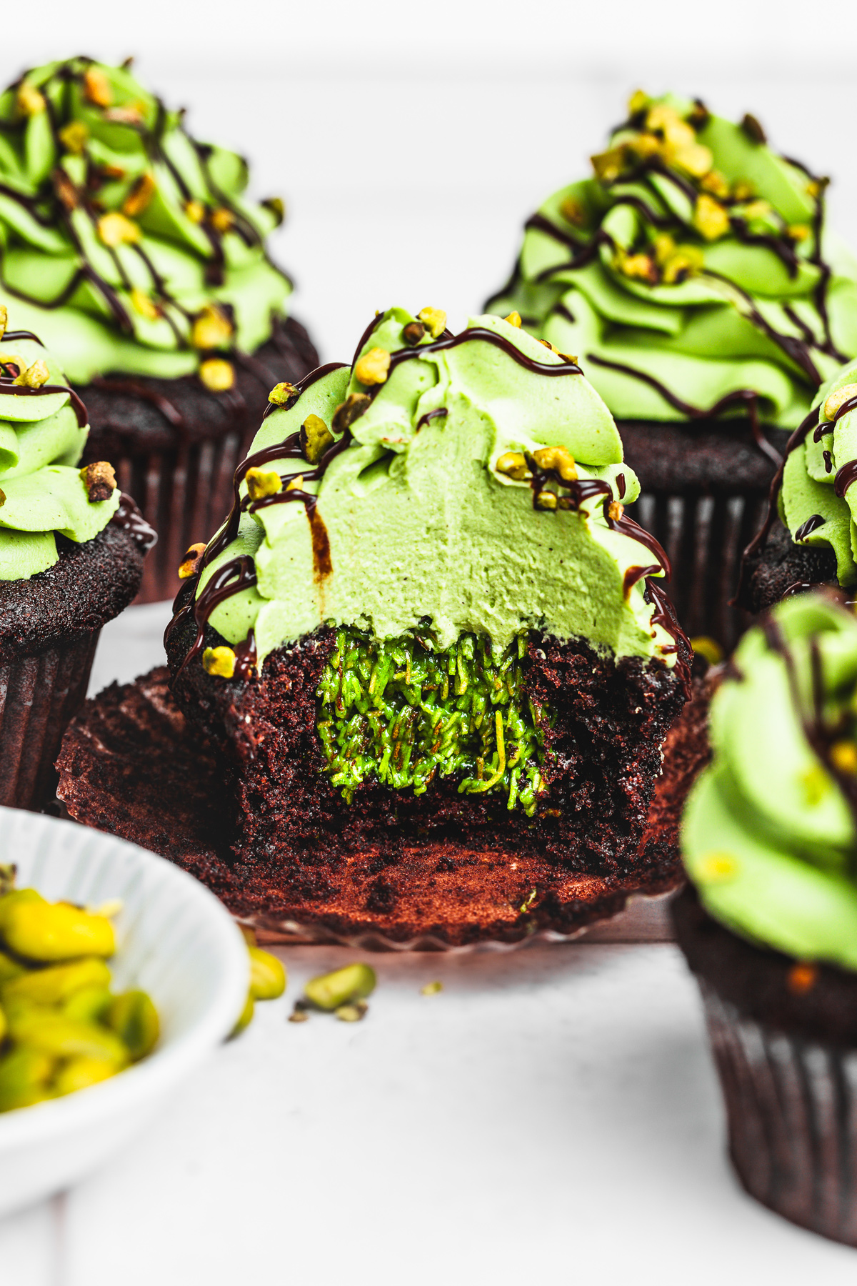 Dubai chocolate cupcakes on a table with a bite showing the inside