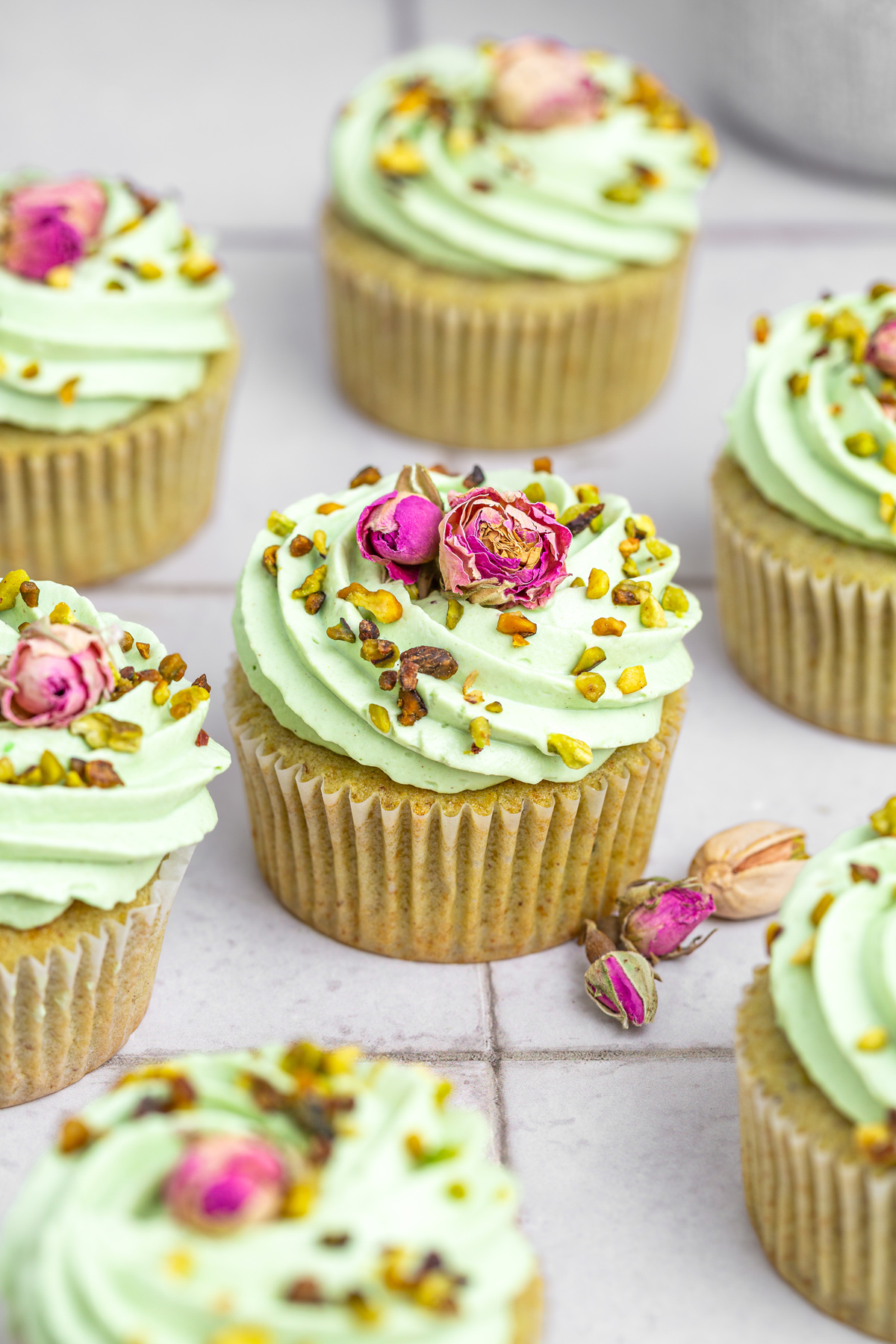 Homemade pistachio cupcakes on a table with creamy frosting