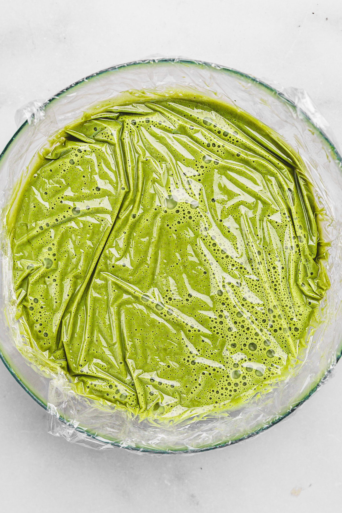 Pistachio ganache covered with plastic wrap to set in the fridge