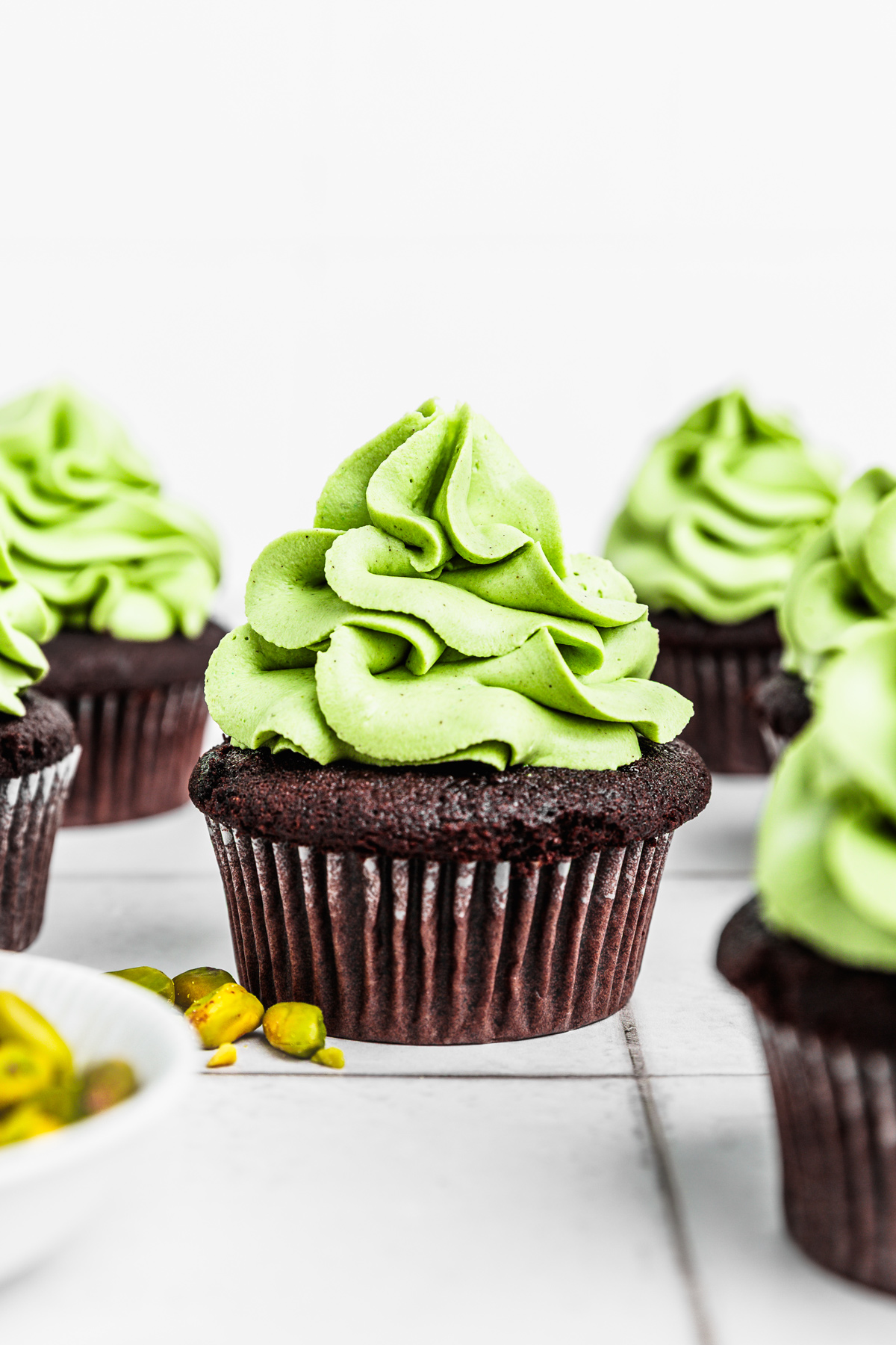chocolate cupcakes topped with whipped white chocolate pistachio ganache frosting