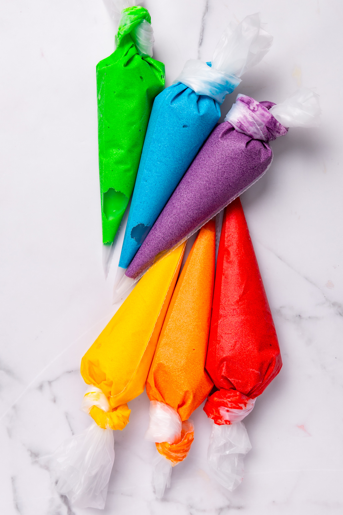 Piping bags filled with colorful cupcake batter for rainbow cupcakes