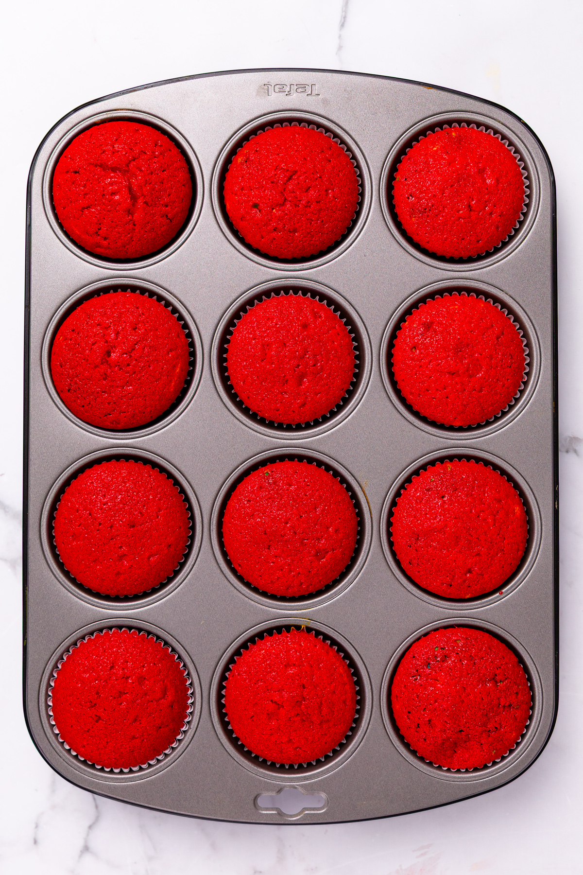 Rainbow cupcakes baked in muffin tin with colorful layers