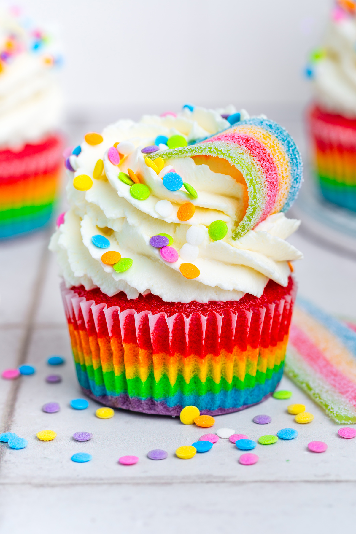 Rainbow cupcake on a table with mascarpone frosting and sprinkles