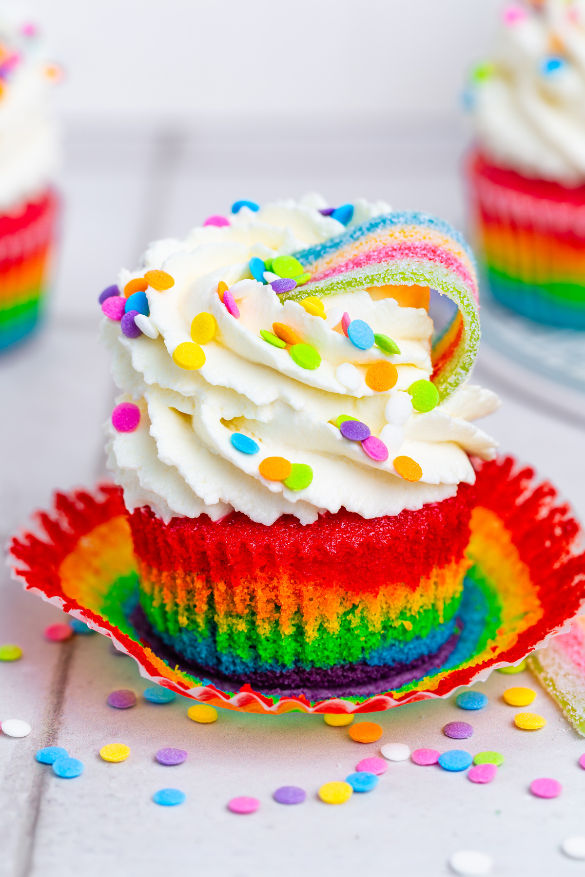 Decorated rainbow cupcakes with whipped mascarpone cream and candy belts