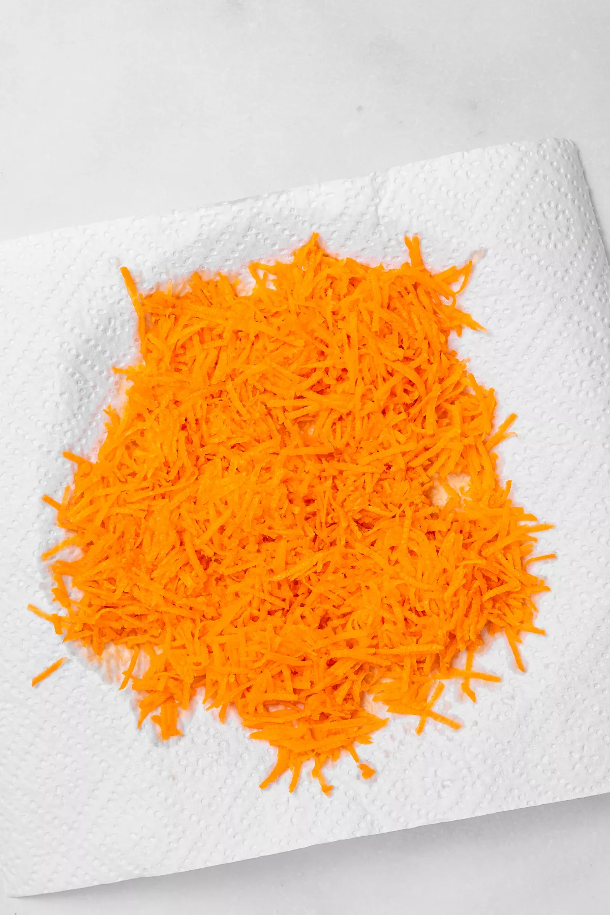 Grated carrots on paper towel for carrot cake cookies