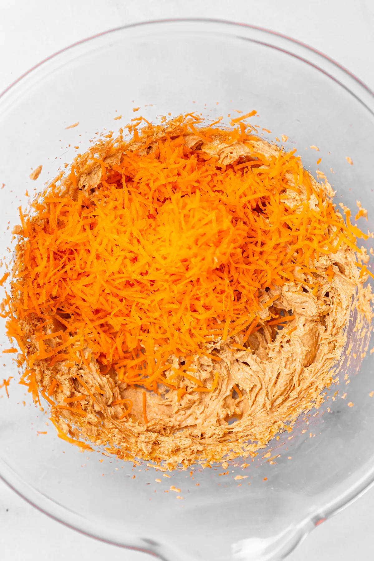 Mixing bowl with cookie dough and grated carrots for carrot cake cookies